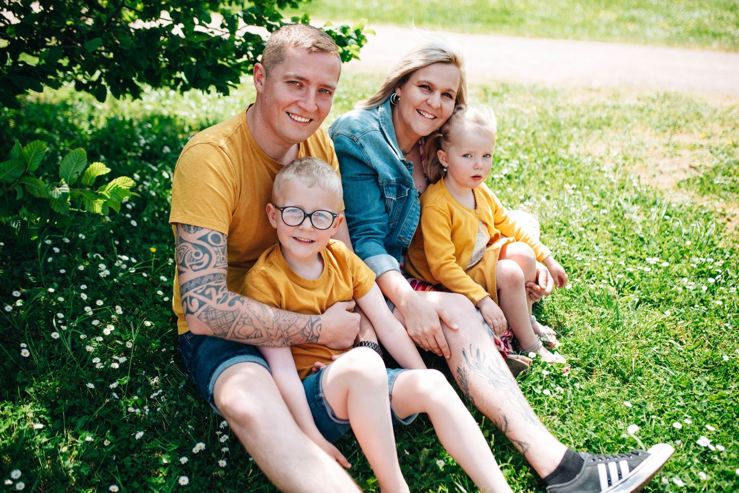 Family members in yellow shirts sitting together on grass in summer.