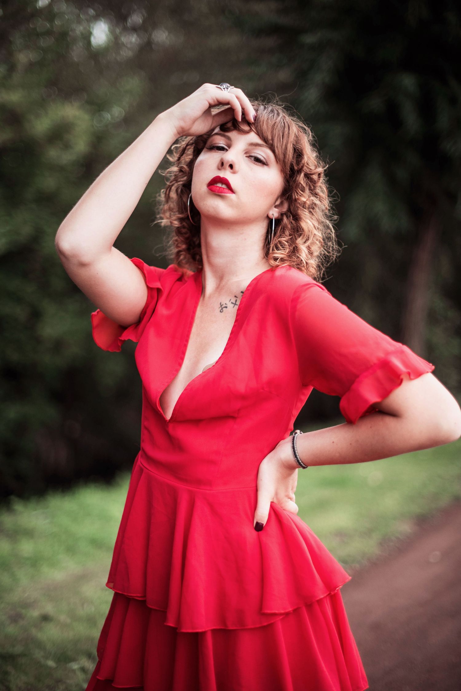 Dramatic outdoor portrait in flowing red dress with ruffled details.