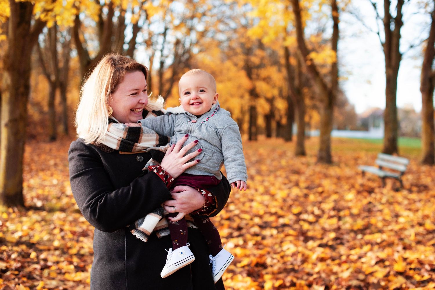 Family enjoying playful moments together on autumn leaves in a park setting.
