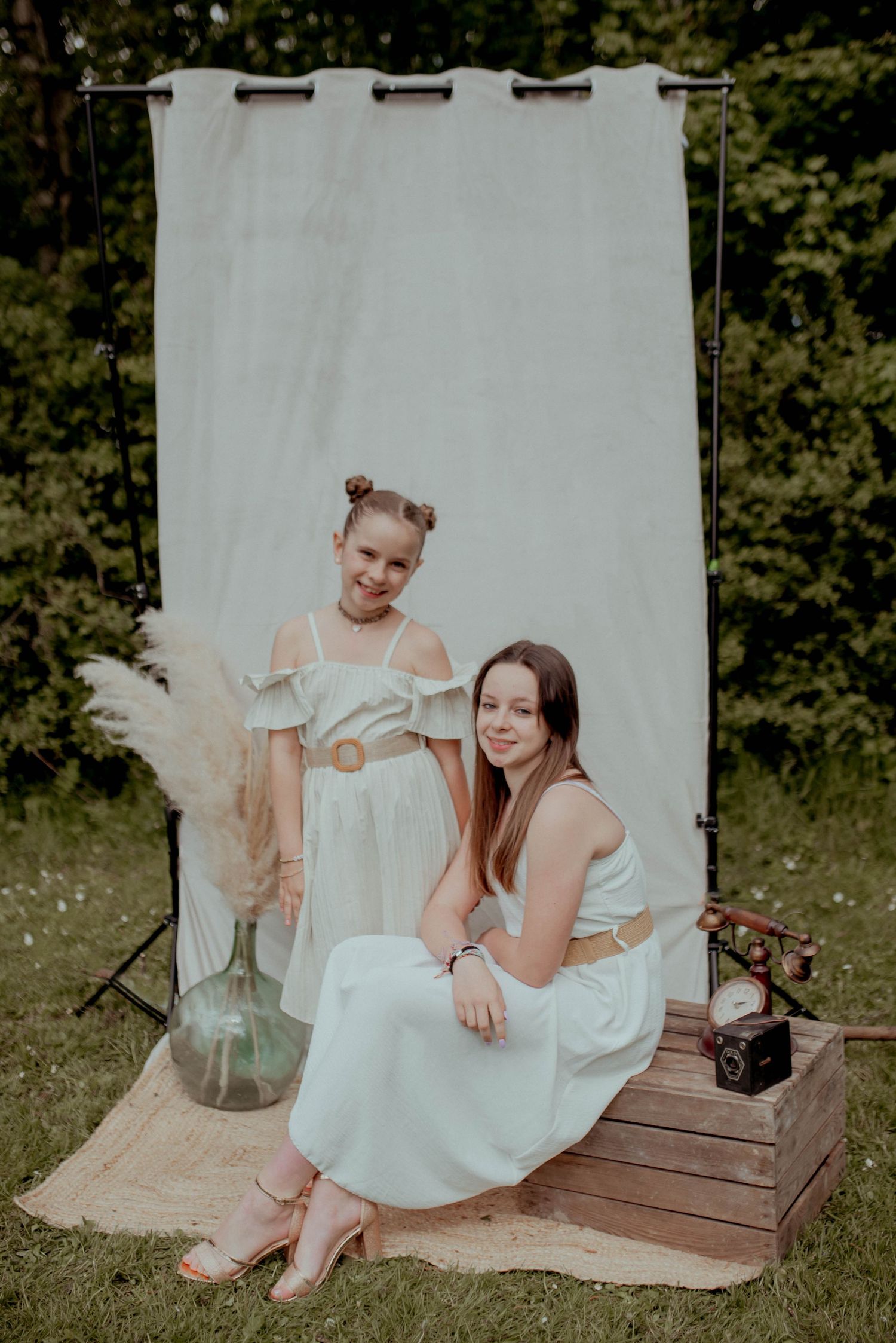 Outdoor portrait session with vintage props and white dresses against a natural backdrop.