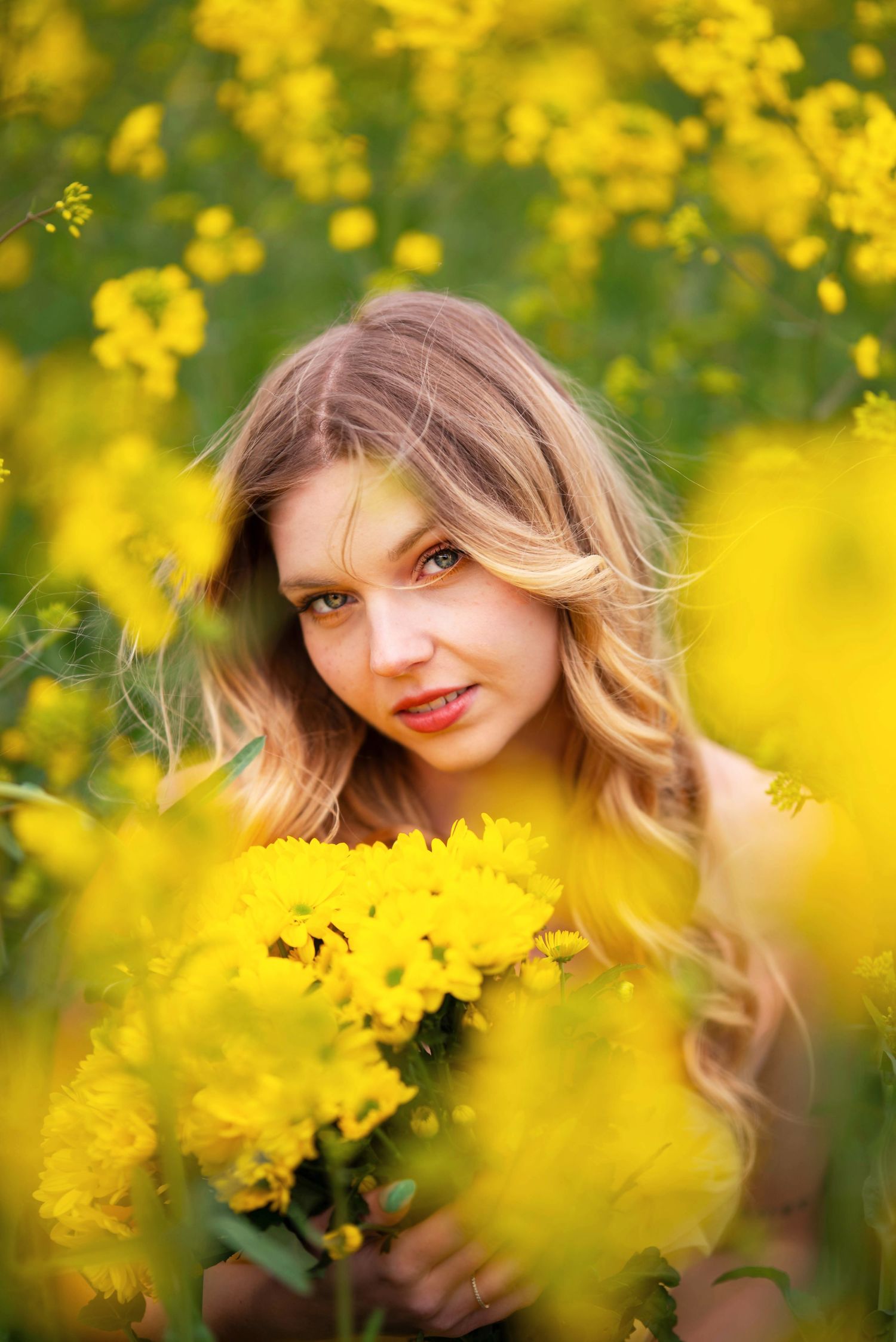 Portrait photography in a field of vibrant yellow flowers with soft natural lighting and bokeh effects.