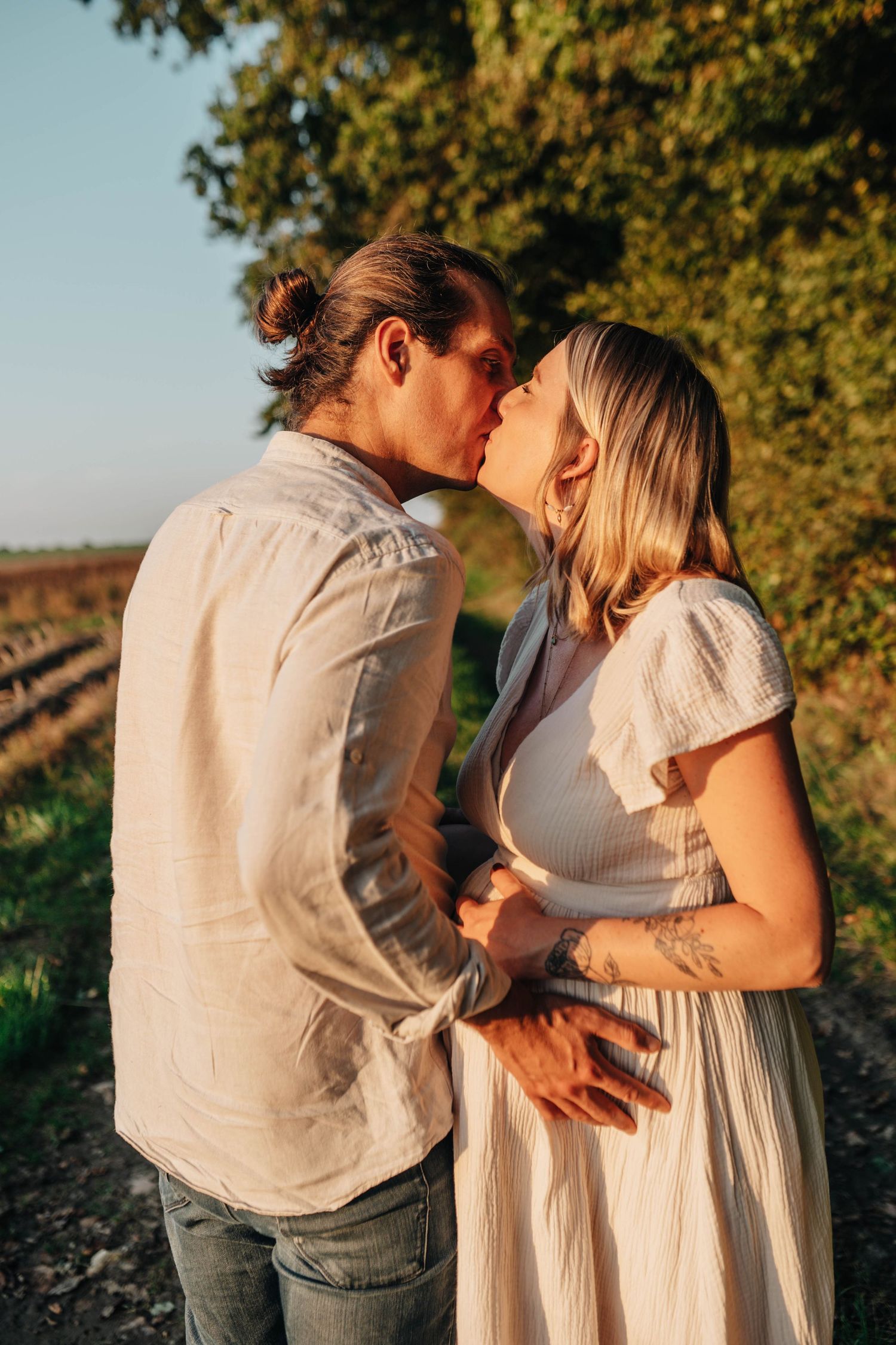 Intimate maternity photos at golden hour showing tender moments between a couple.