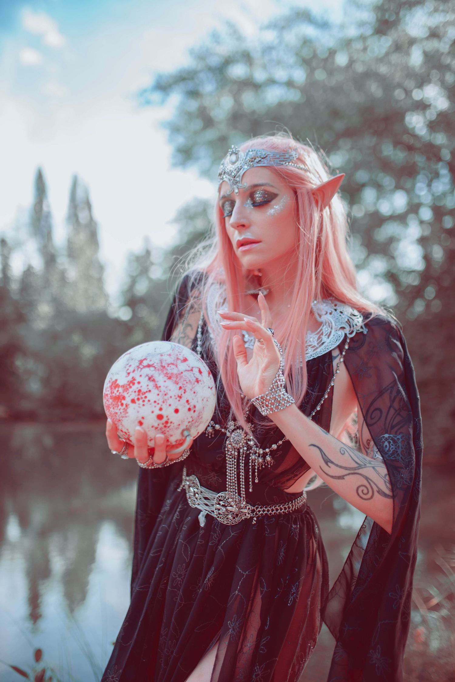 Fantasy themed portrait with pink hair and crystal ball in mystical forest setting.