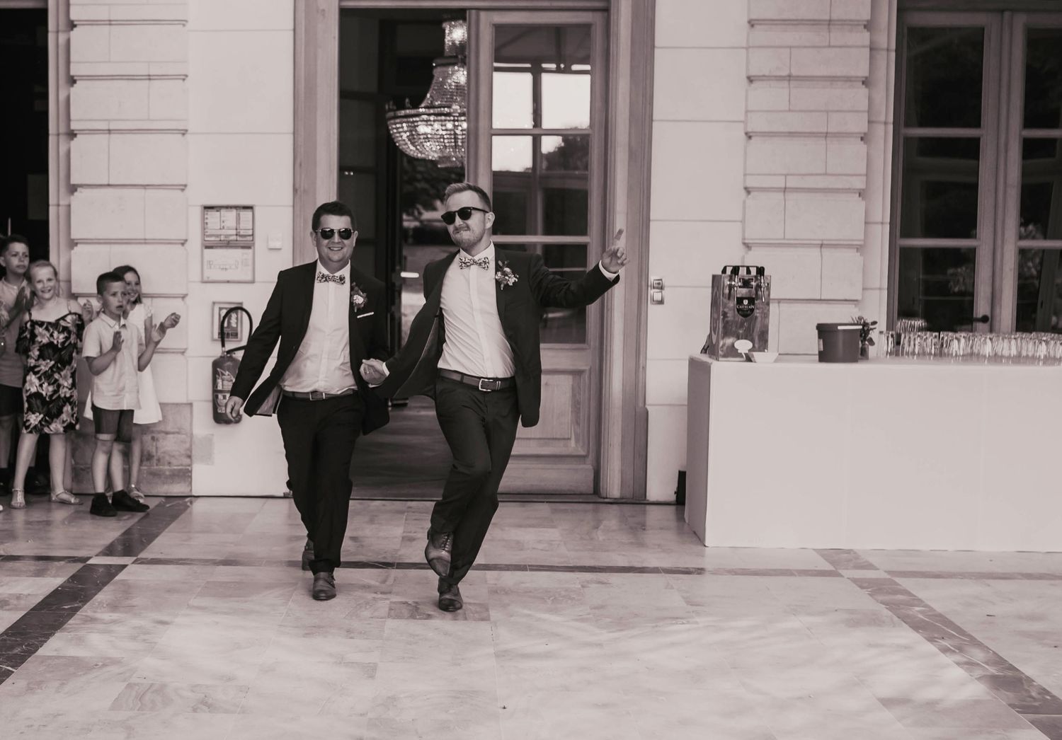 A black and white photo of two people in suits joyfully exiting a building together.