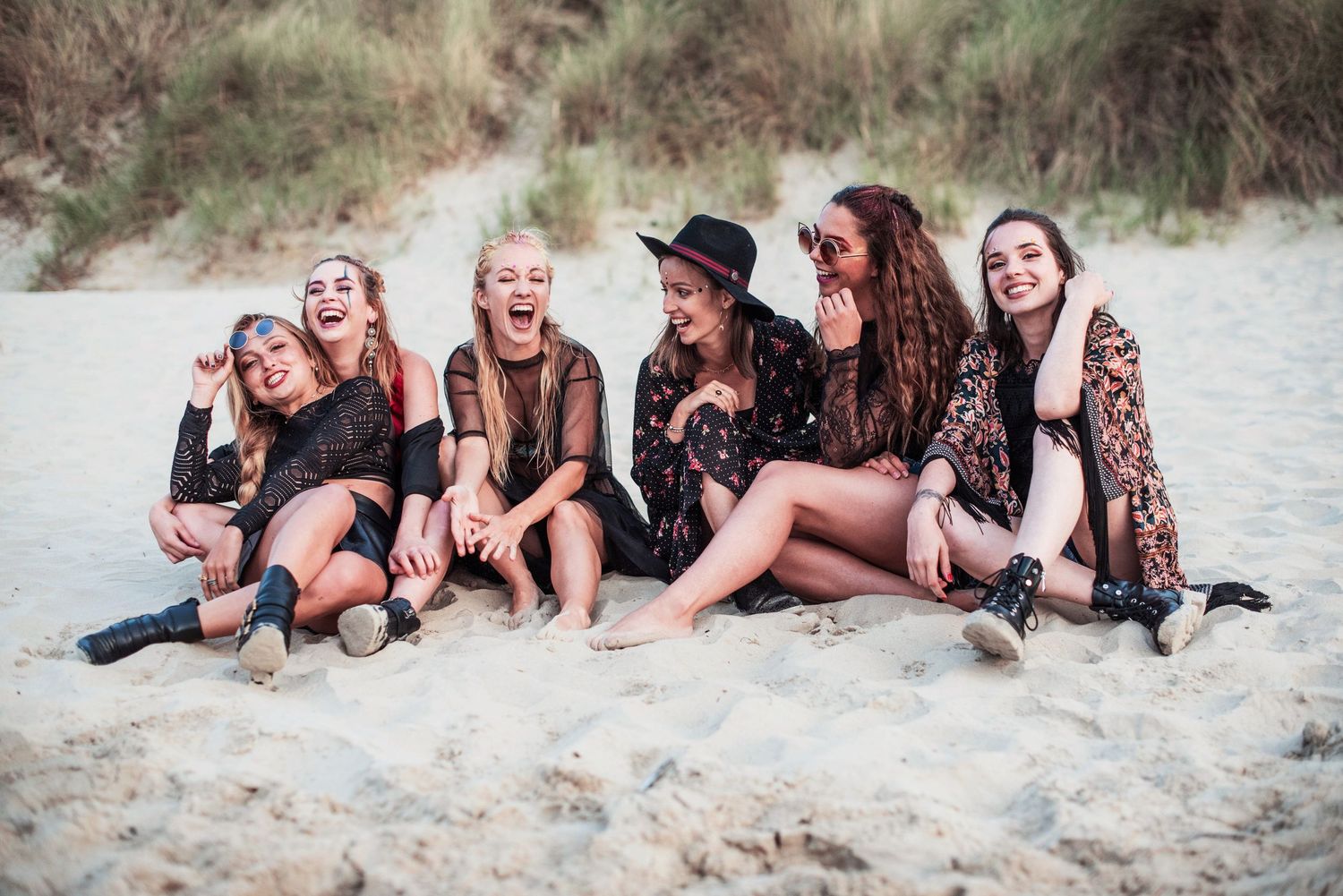 Group lounging together on sandy beach during casual photo session.