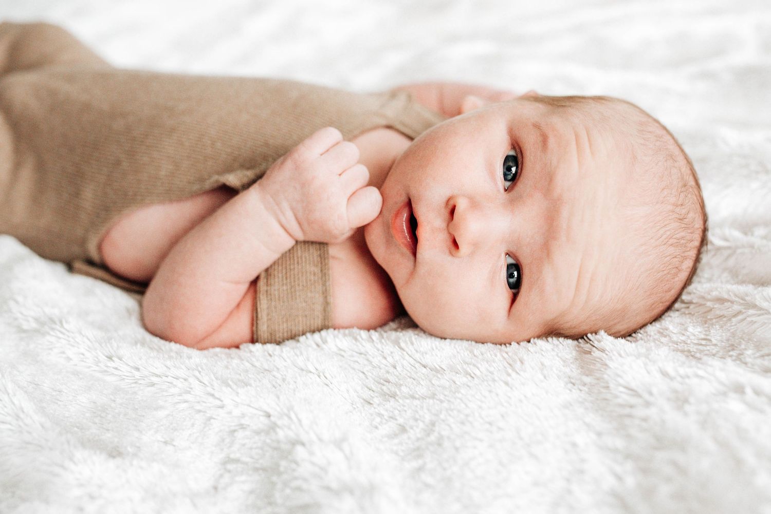 A baby lying on white lace fabric in a series of gentle poses.