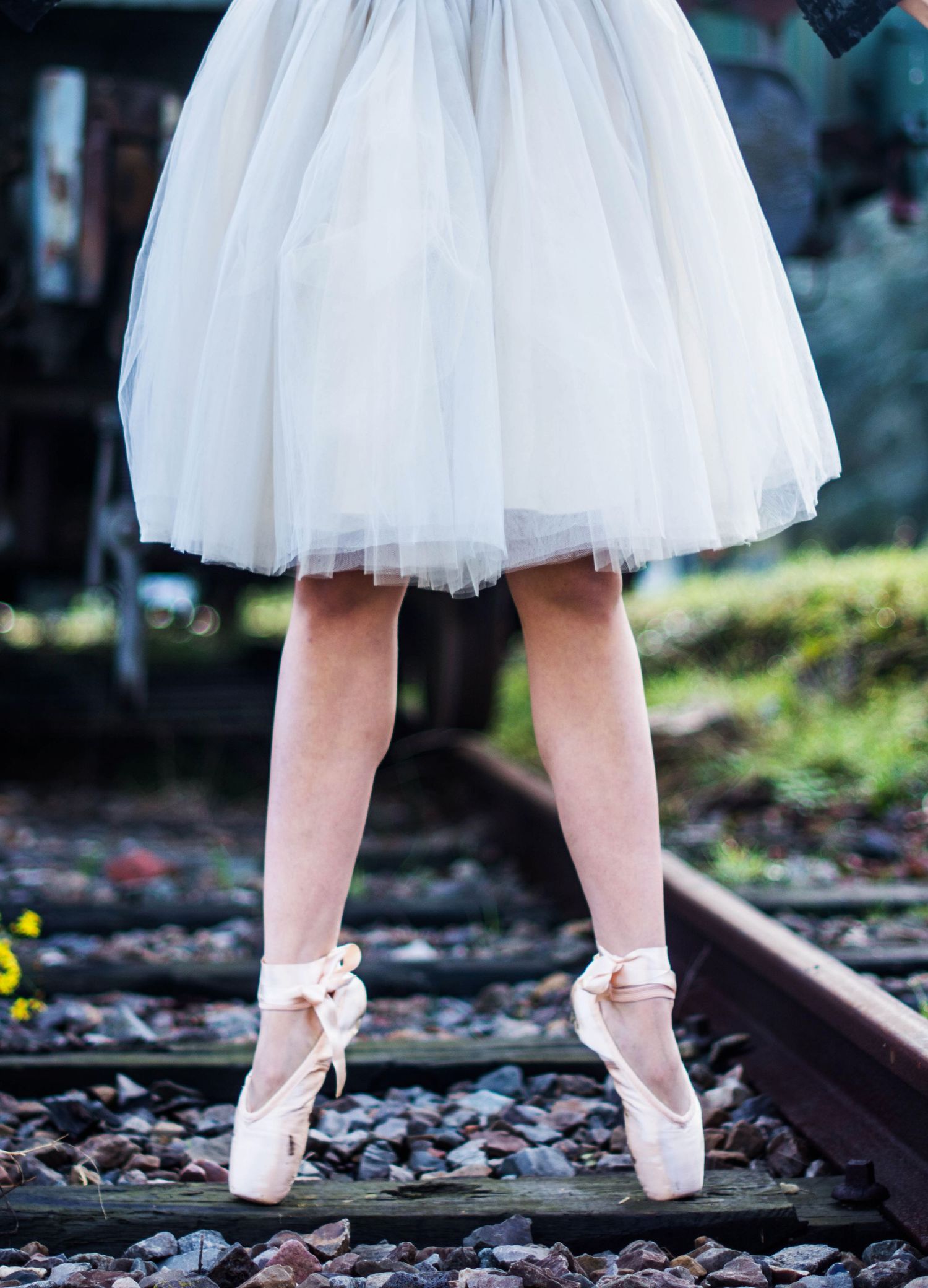 Ballet shoes and tutu detail shot on railroad tracks with artistic composition.