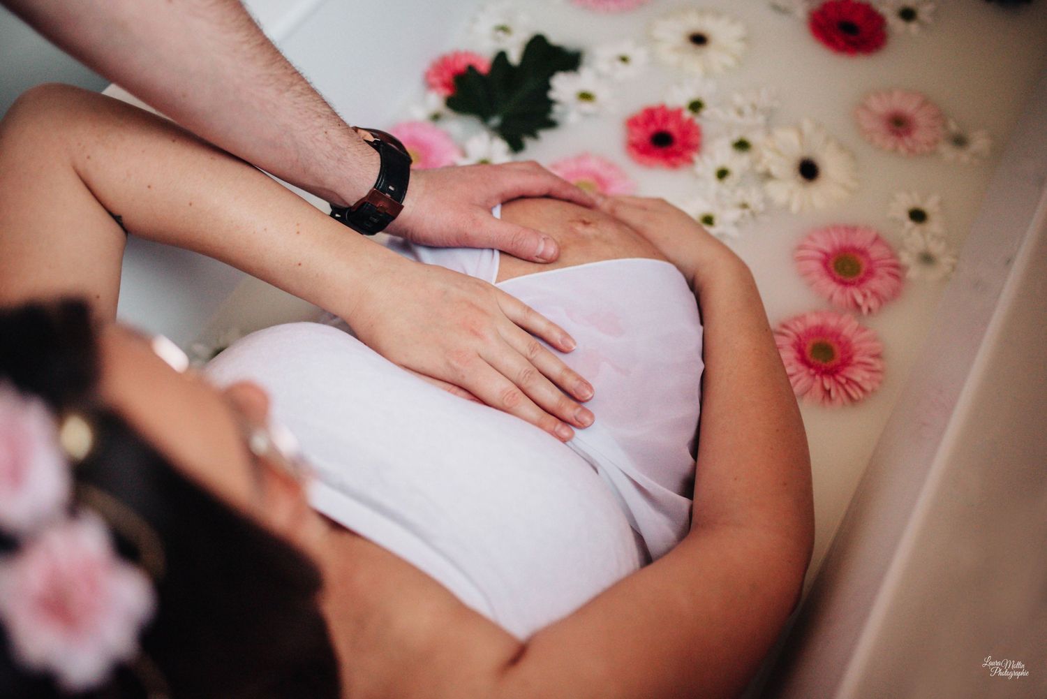 Close-up details of hands tenderly touching a pregnant belly with floral decorations.