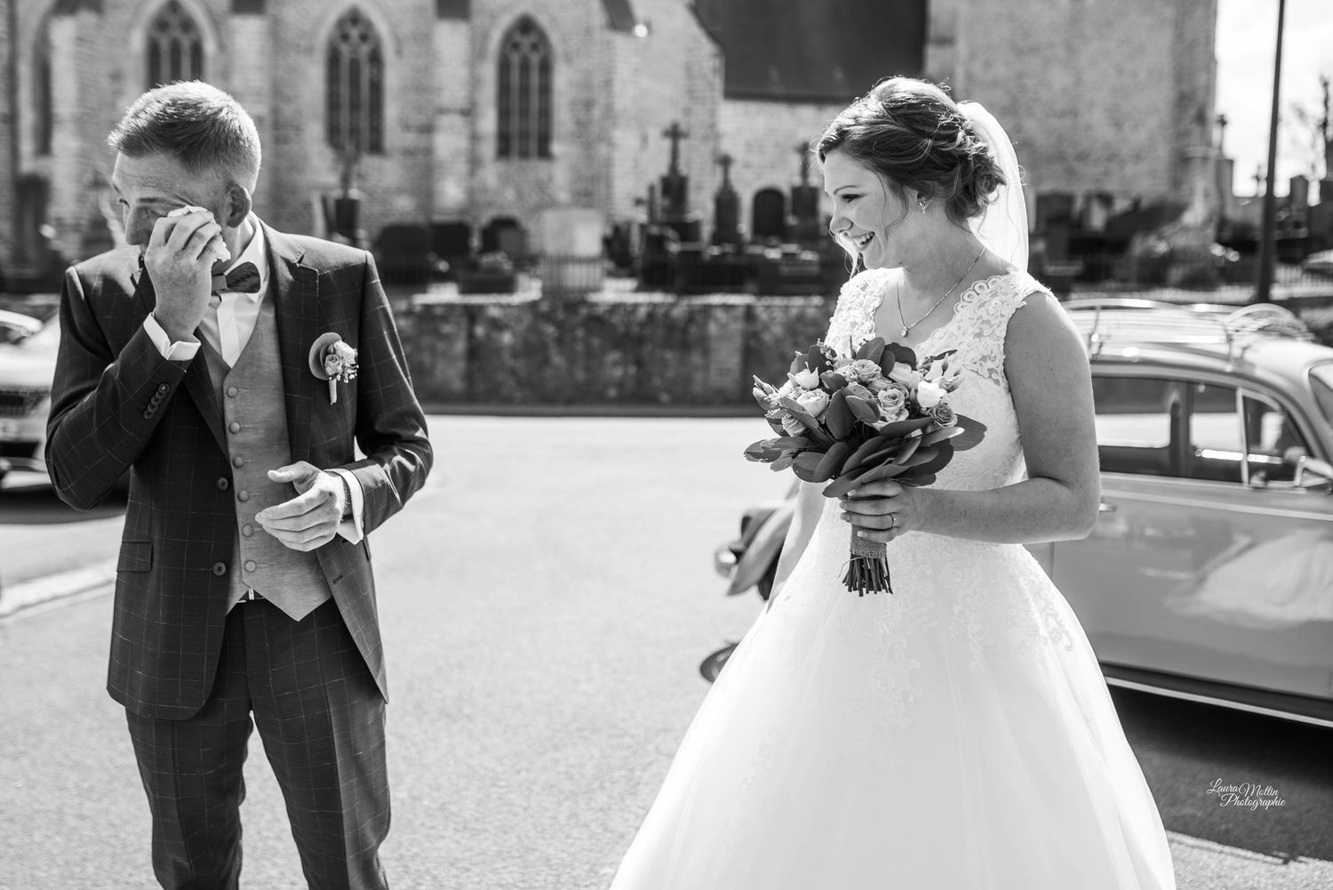 A couple shares a romantic moment in front of a stone building with elegant columns.