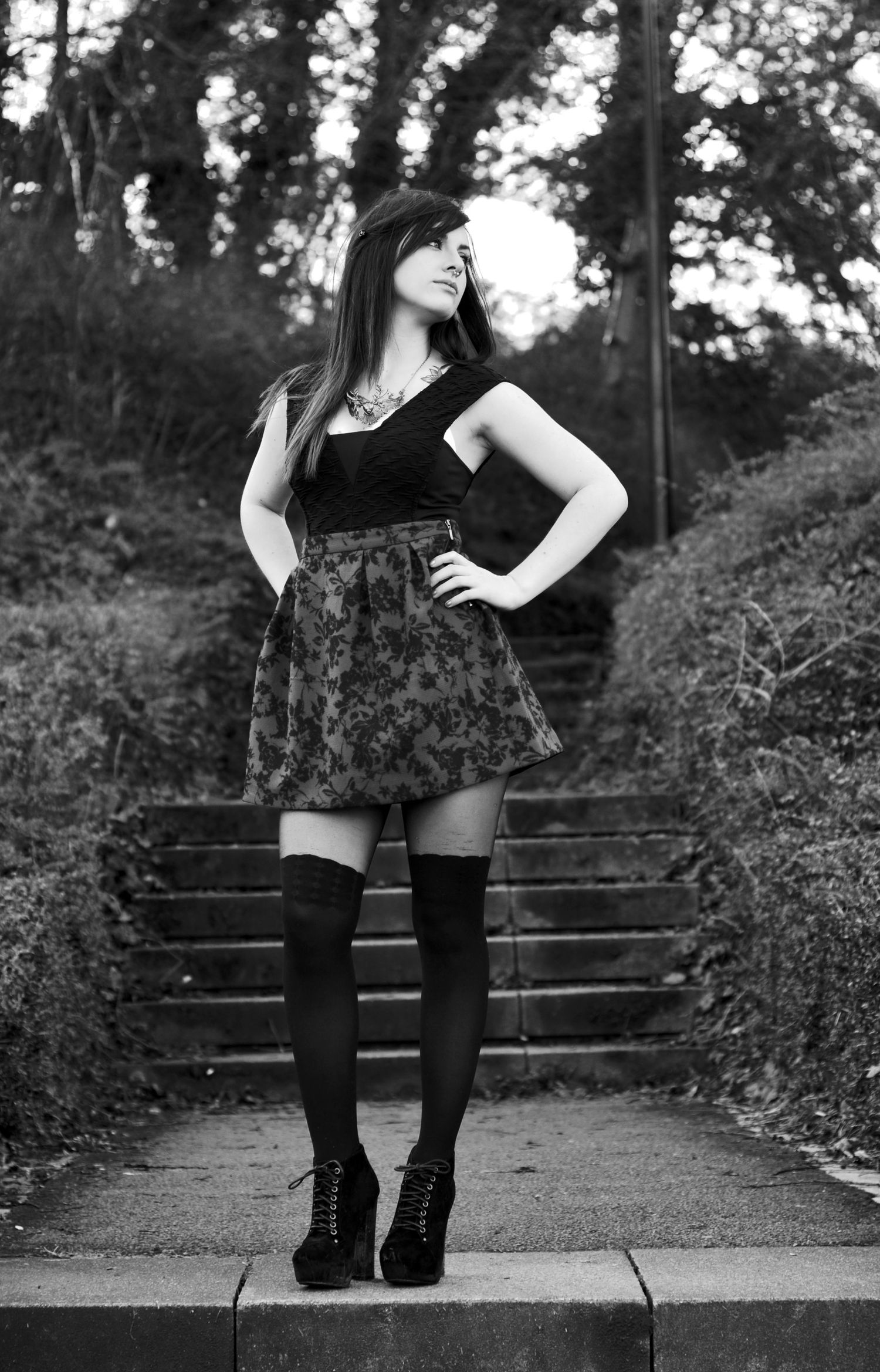Black and white portrait on stone steps featuring floral skirt and knee-high socks.