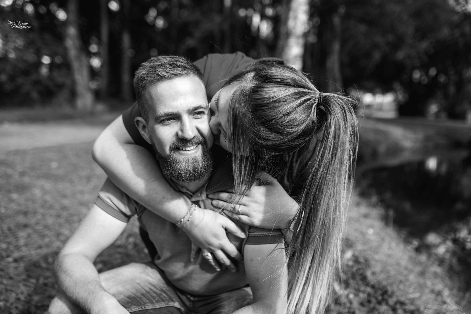 Black and white portrait of playful couple sharing joyful moment in park setting.