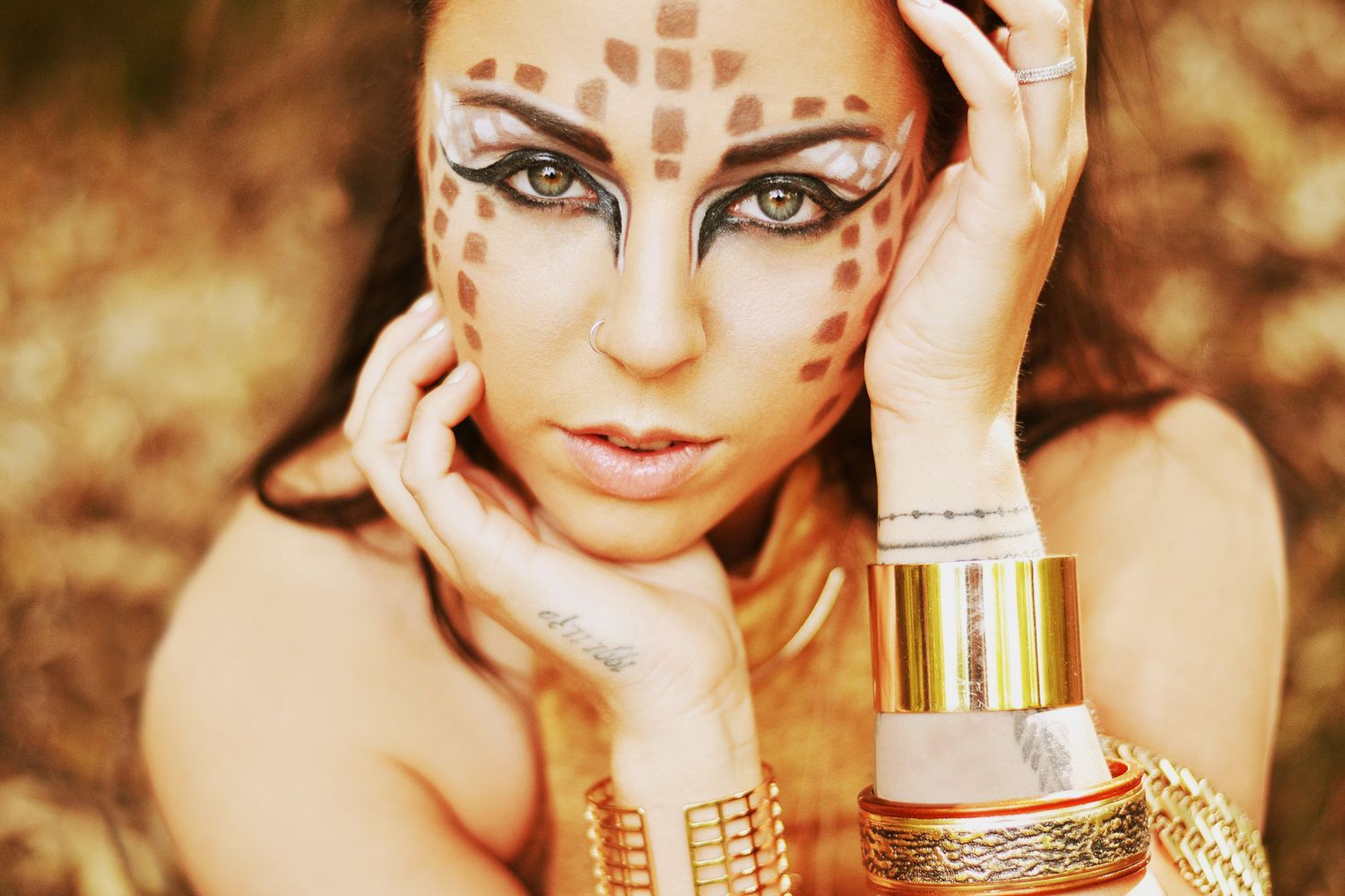 Close-up beauty portraits with ornate gold face decorations and dramatic lighting.