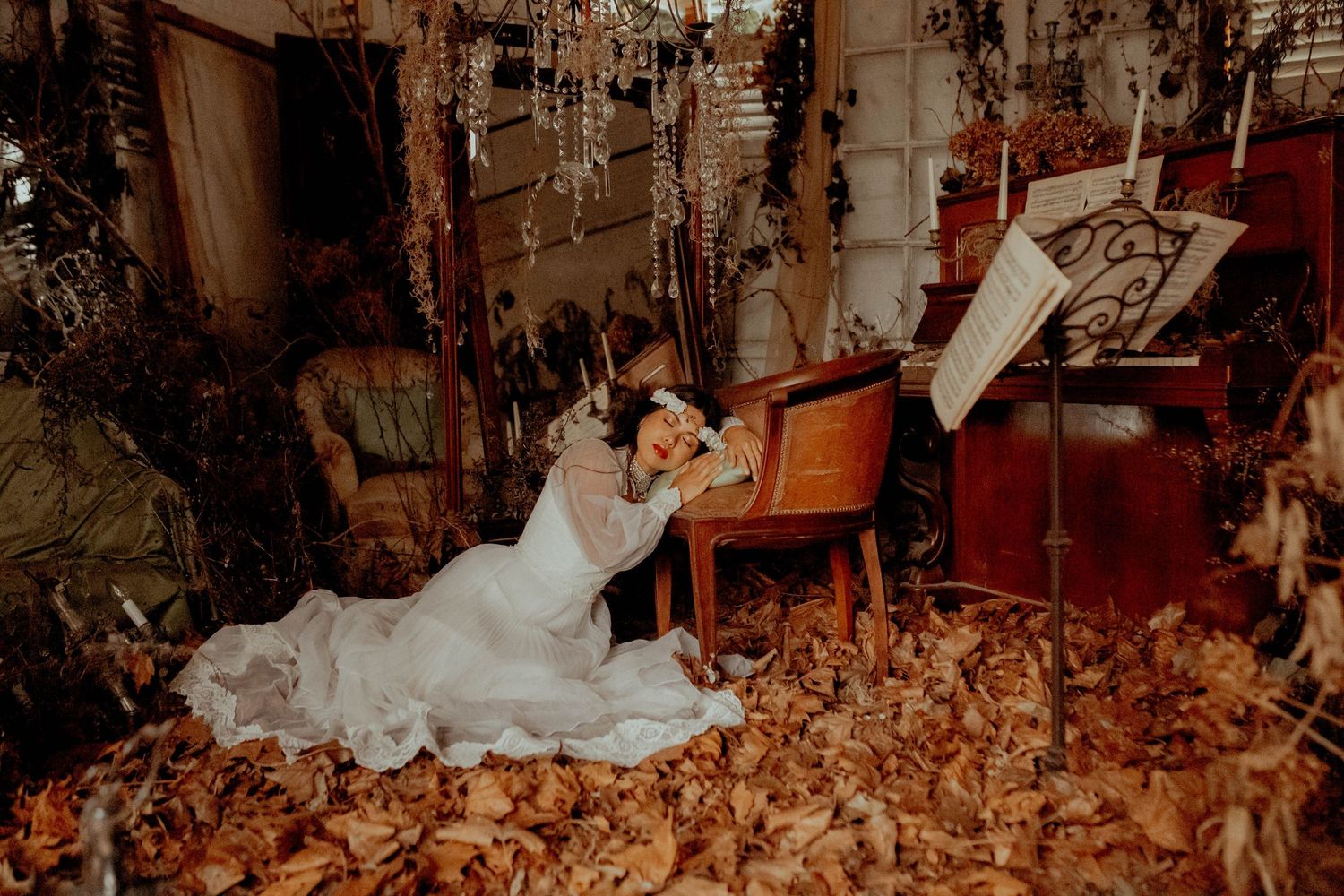 Artistic portrait on autumn leaves featuring flowing white fabric in dramatic lighting.