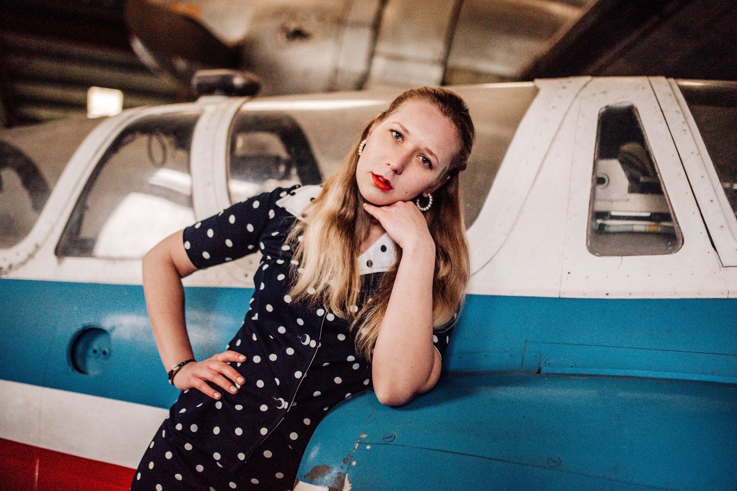 Retro-styled photoshoot featuring a blue and white small aircraft in a hangar.