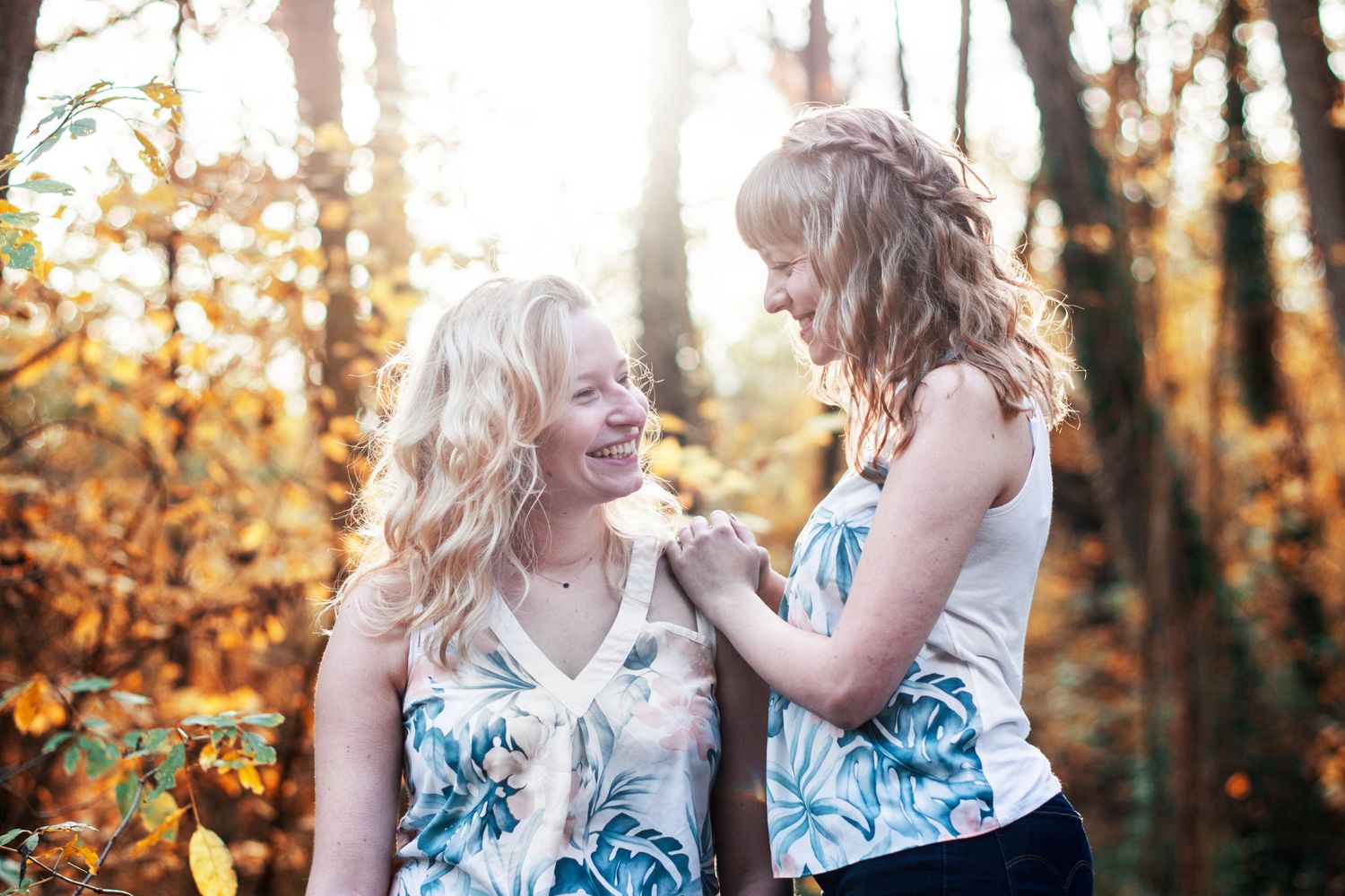 Two people in floral outfits sharing joyful moments in an autumn forest setting.
