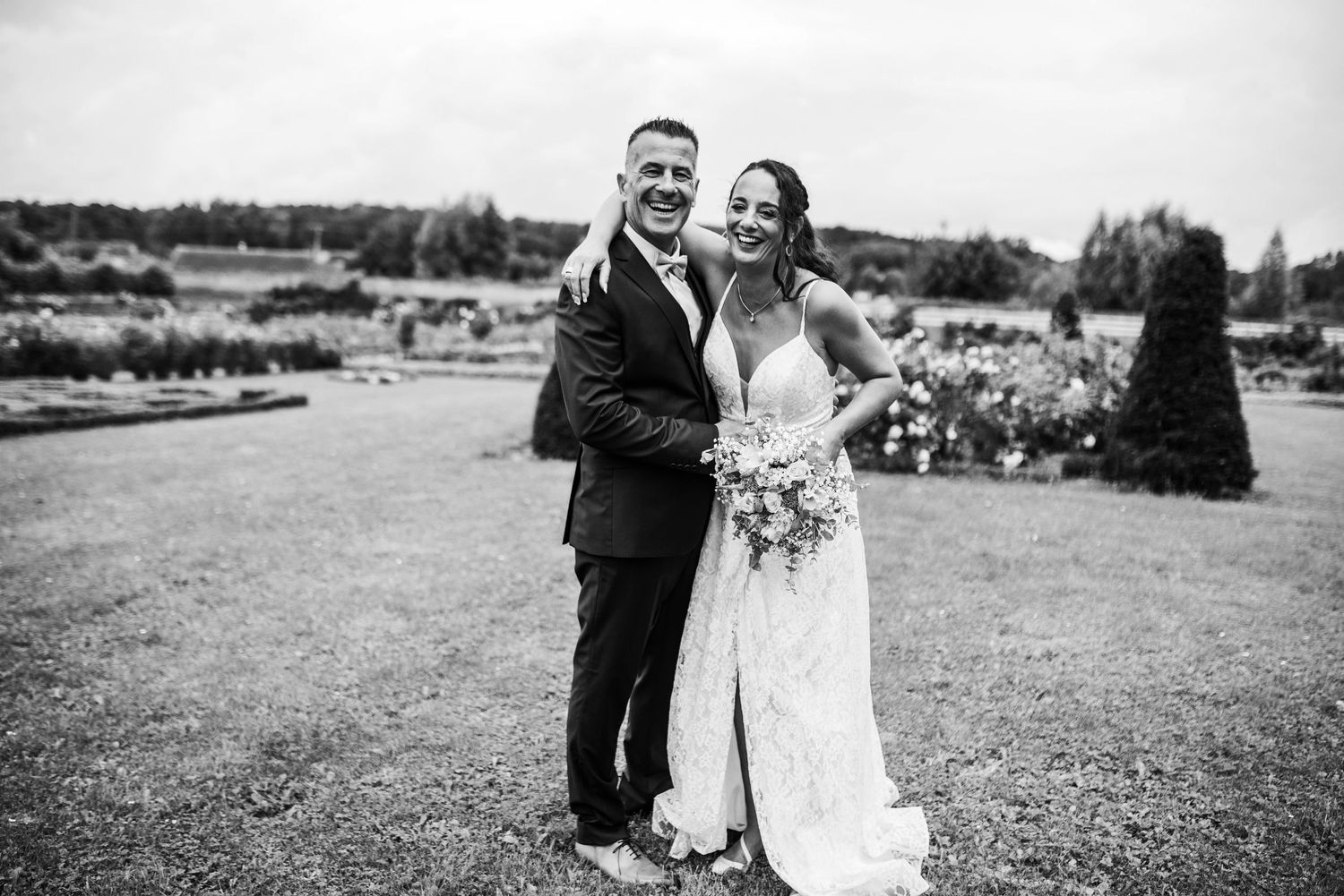 Black and white photo of newlyweds walking together in an outdoor setting.