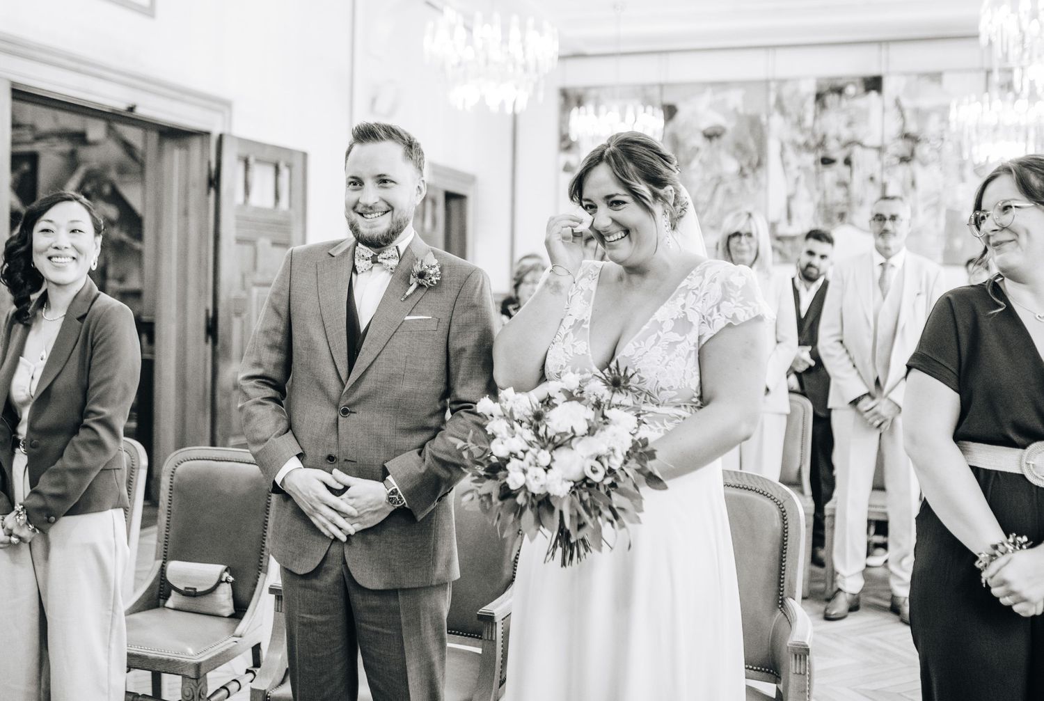 Black and white photo of a joyful wedding ceremony moment in an elegant indoor setting.