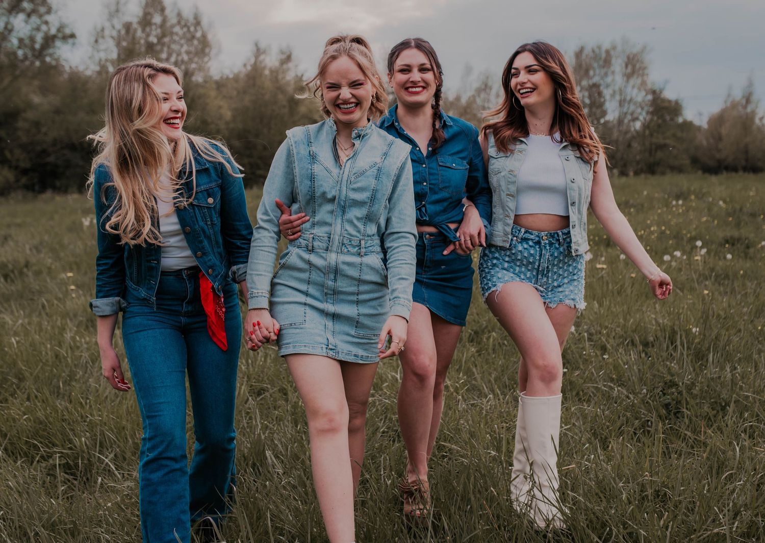 Friends laughing together while posing casually in a grassy field.