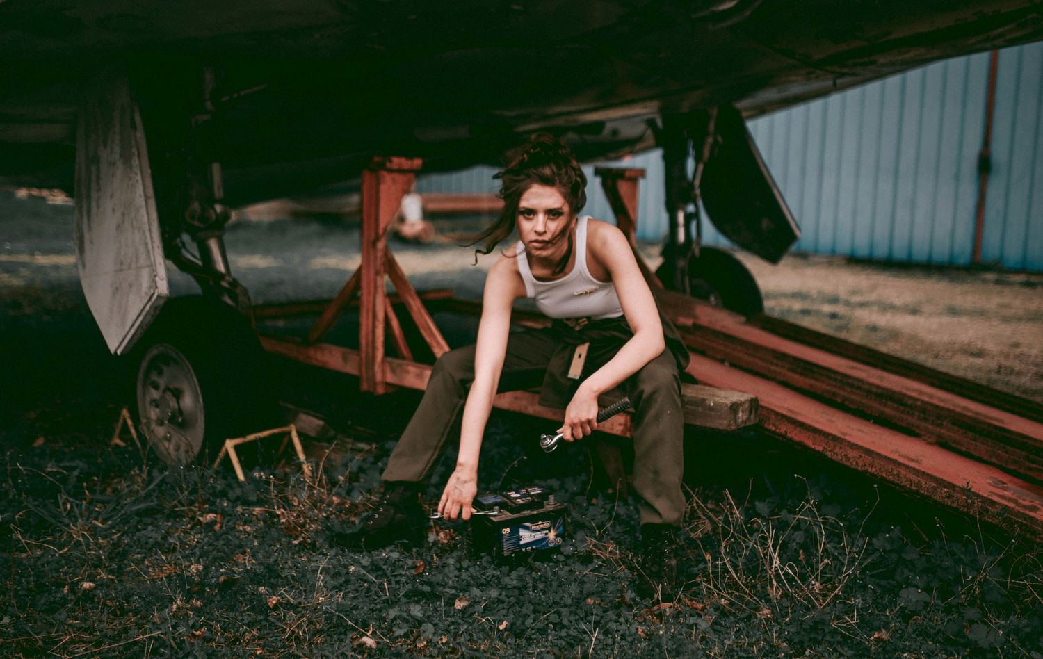 Figure in casual attire working on mechanical equipment in a dimly lit workshop setting.
