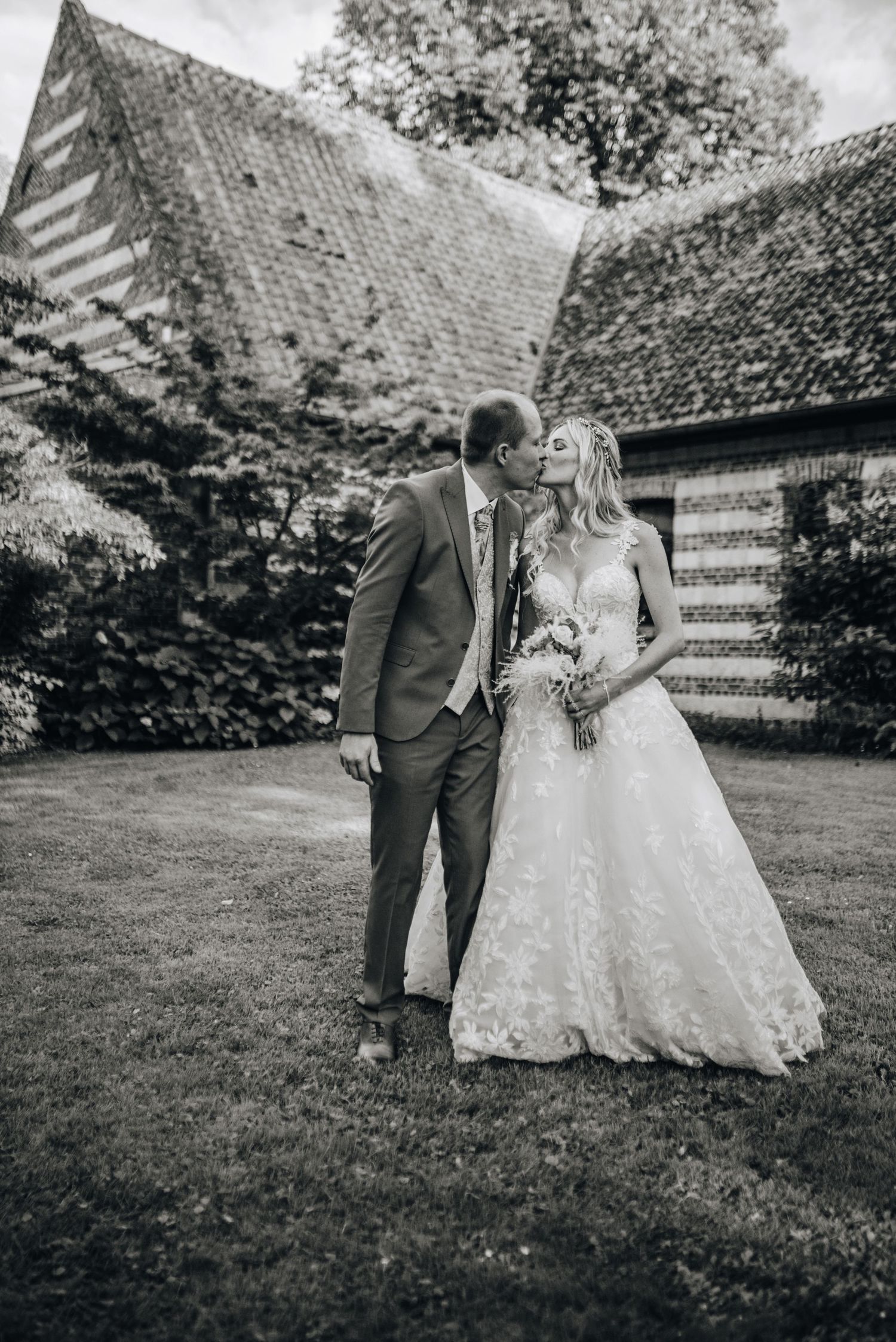 Black and white wedding portraits taken against rustic brick building backdrop.