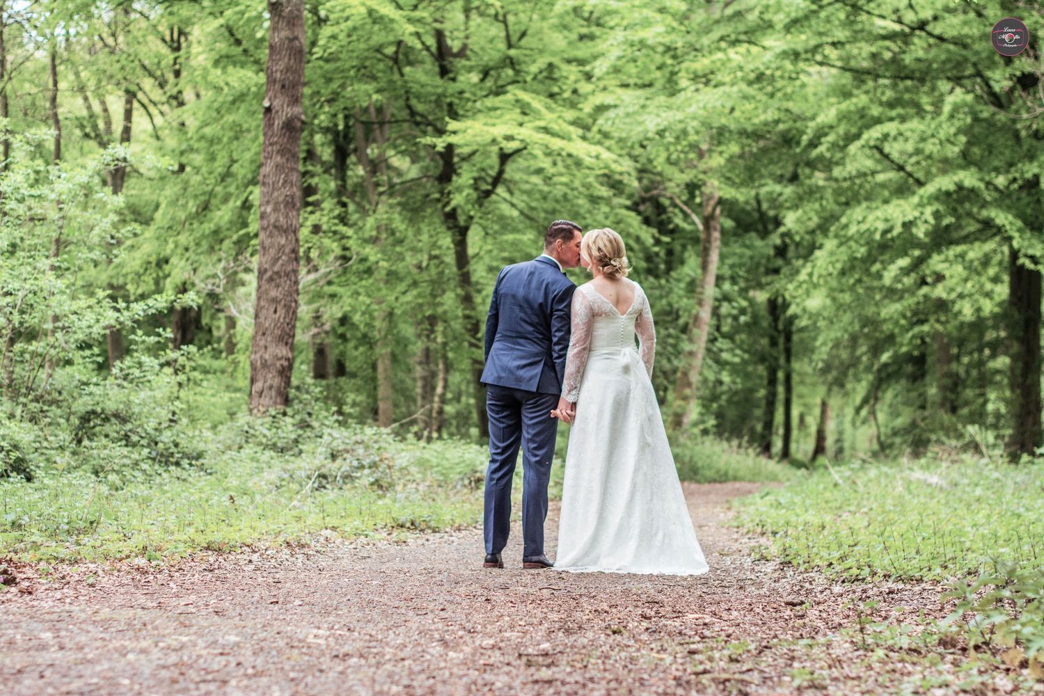 Couple walks through a lush green forest setting on their wedding day.