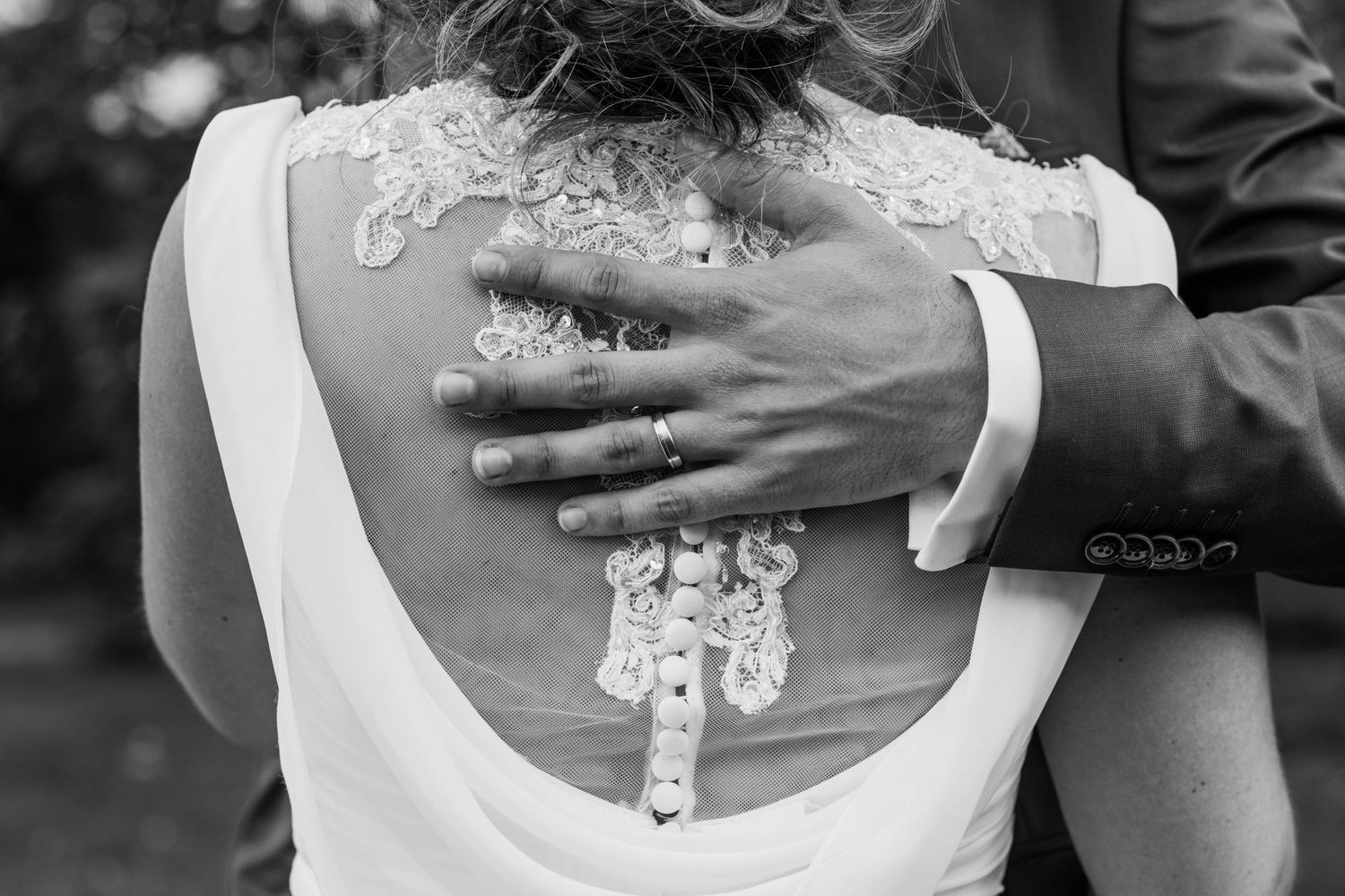 Close-up details of white lace wedding dress bodice and buttons.