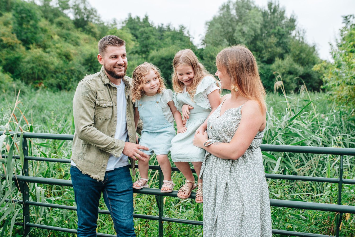 Family walking together on a rustic bridge surrounded by lush greenery.