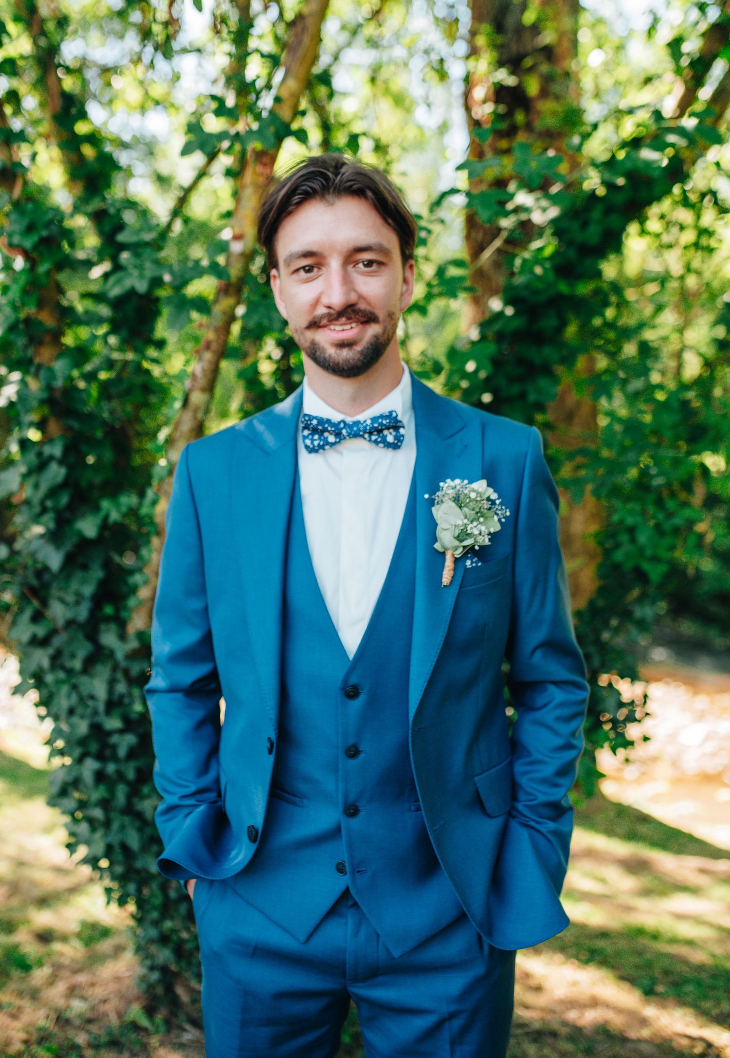 Groom wearing bright blue three-piece suit with polka dot bow tie and boutonniere.