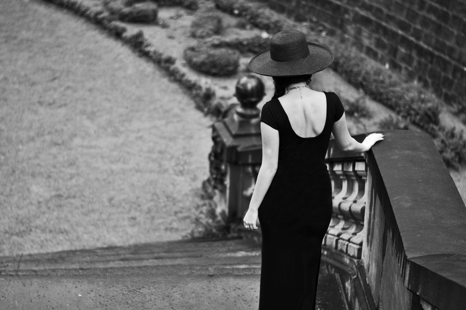 Elegant black evening gown photographed in dramatic black and white on garden steps.