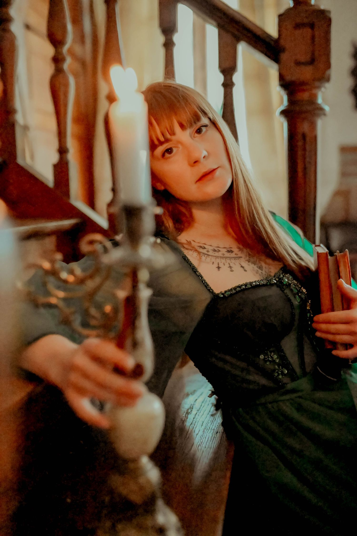 Moody indoor photoshoot with vintage candelabra and wooden banister elements.