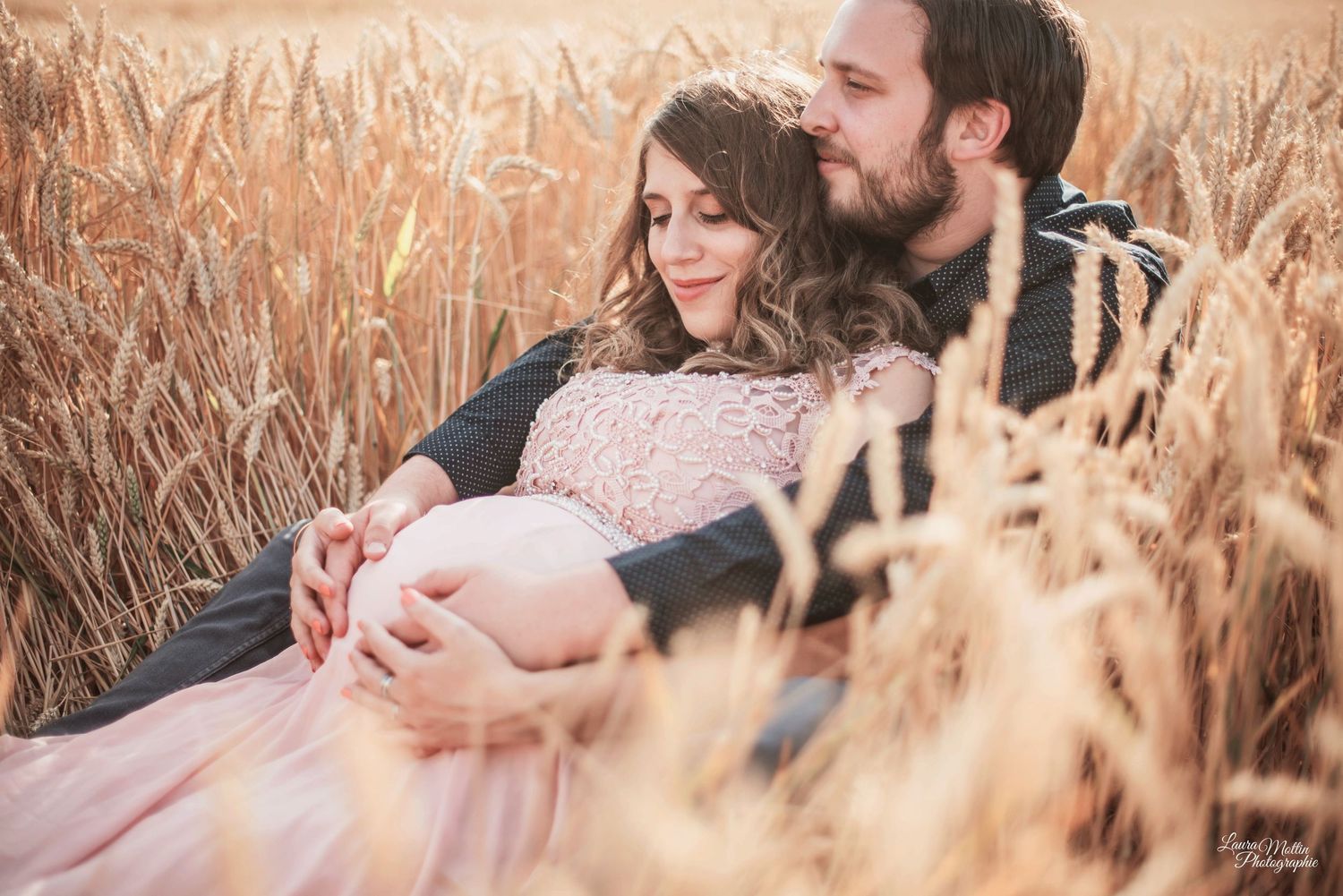 Romantic couple's portrait session in golden wheat field at sunset.