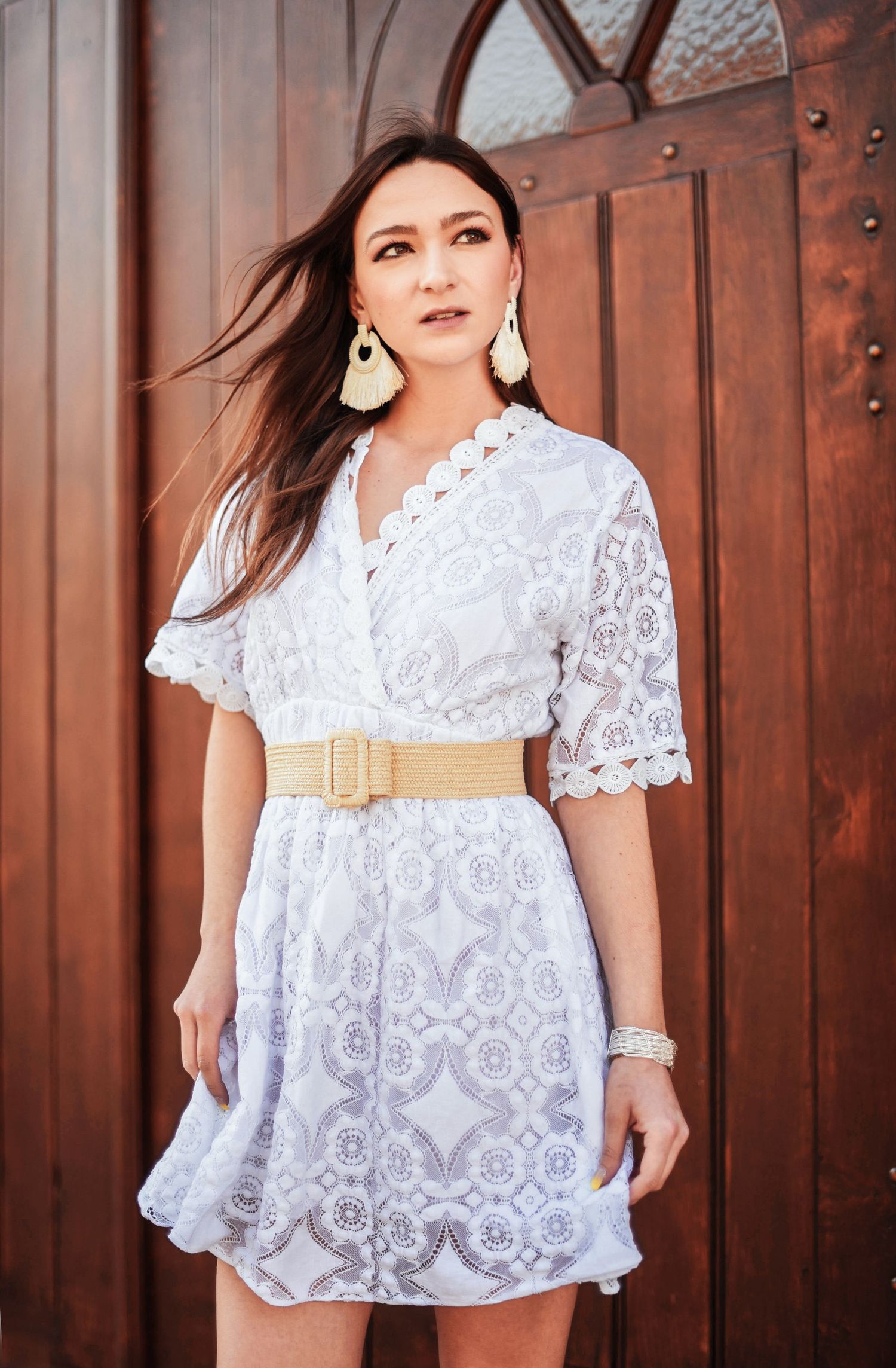 Bohemian style photoshoot featuring white lace dress against wooden door background.