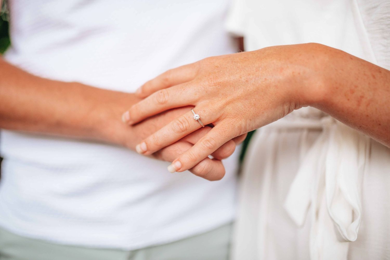 Close-up sequence focusing on hands and wedding rings against white clothing.