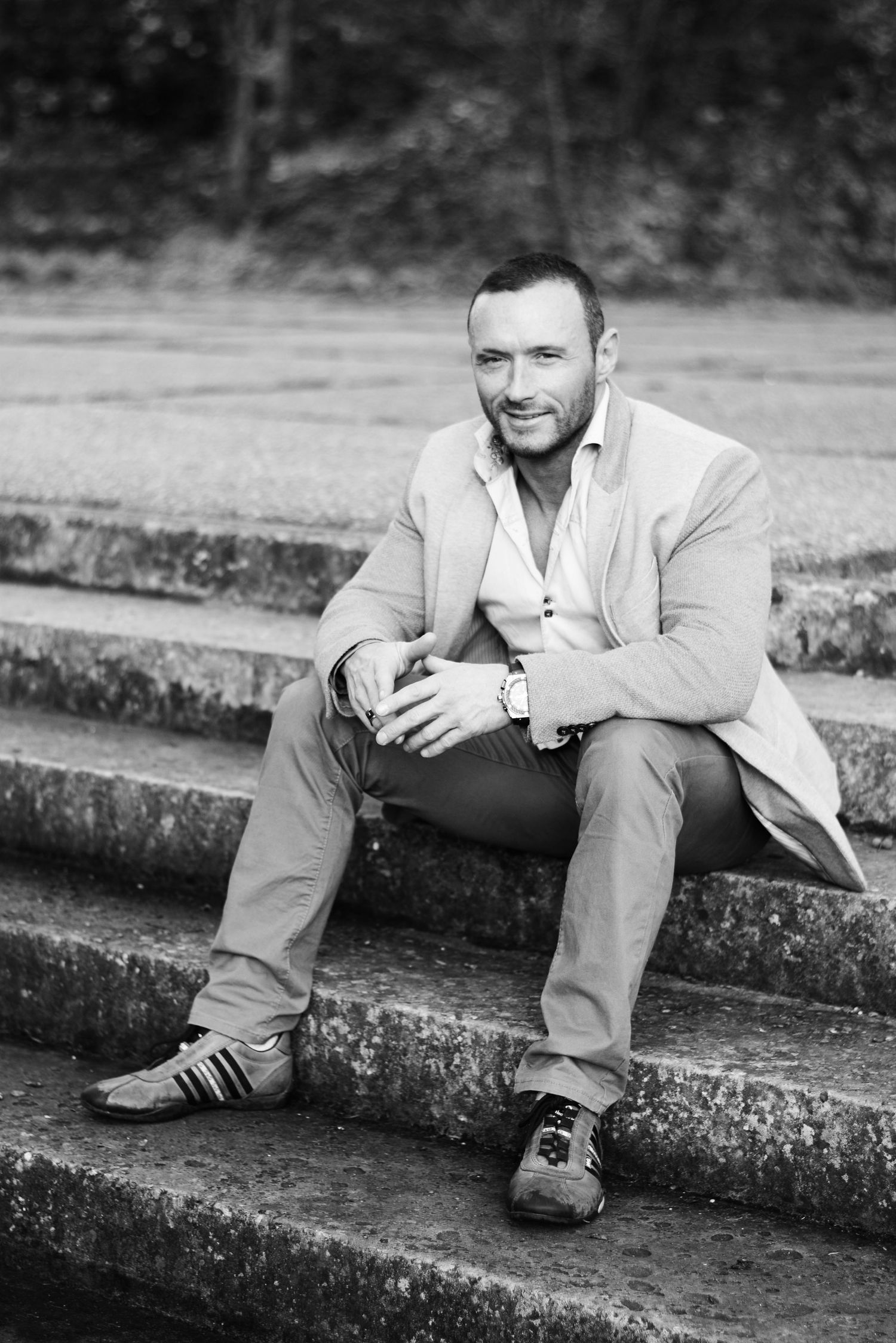 Black and white portrait of person in light clothing seated on outdoor stone steps.