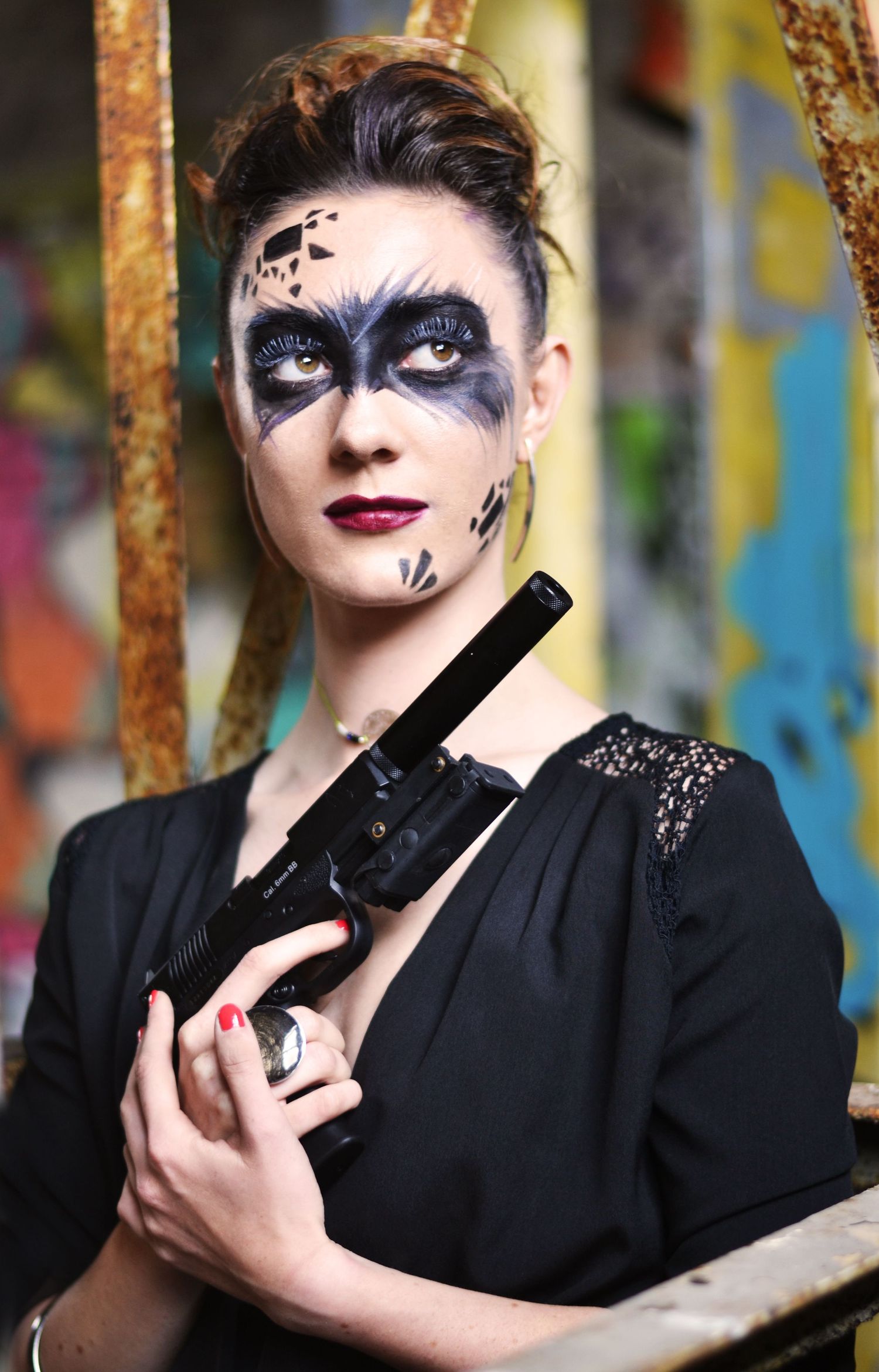 Gothic inspired portrait with dramatic makeup against urban graffiti background.