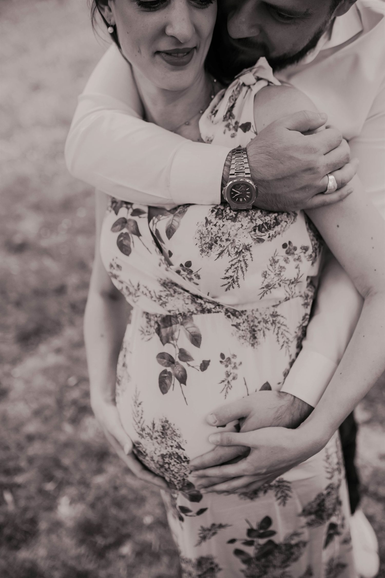 Black and white maternity portraits showing gentle embraces in floral dress.