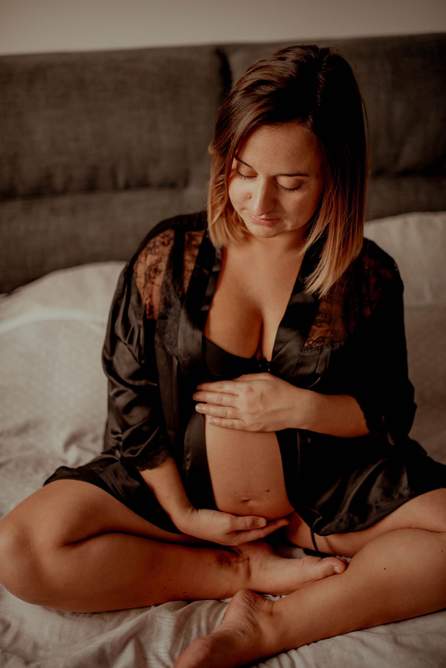Artistic black and white maternity photos showing tender moments on bed.