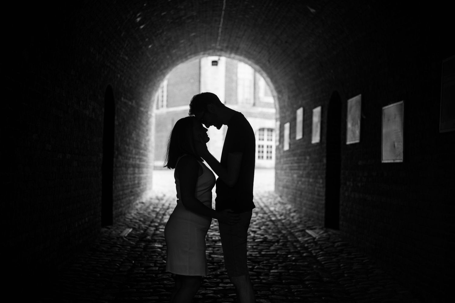 Silhouettes of a couple embracing in a dramatic tunnel with backlight.