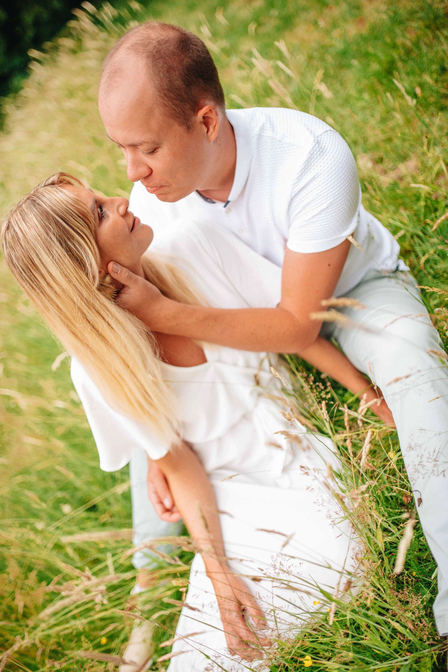 Romantic sequence of a couple in white clothing sharing intimate moments in tall summer grass.