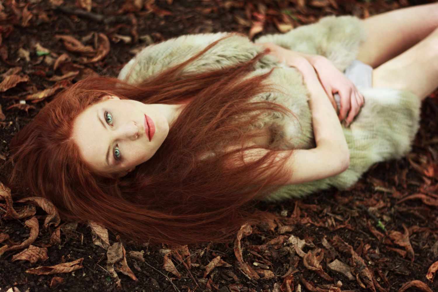 Artistic portrait on fallen autumn leaves with soft natural lighting.