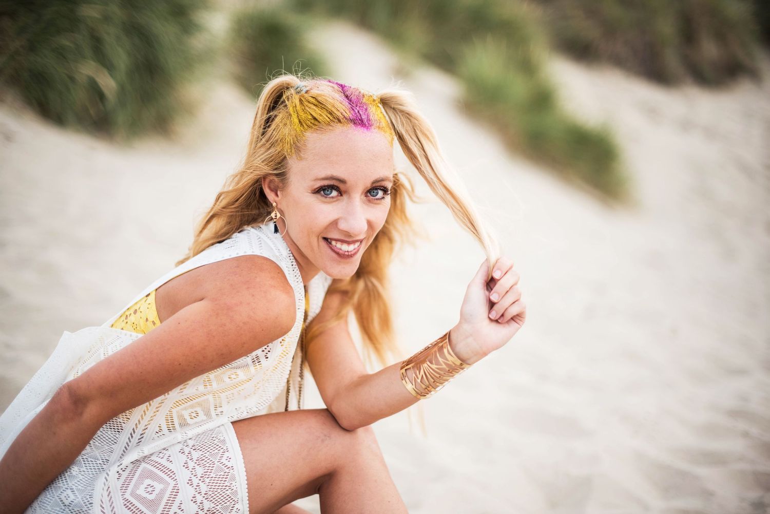 A beachside photoshoot featuring casual summer attire against sand dunes and coastal vegetation.