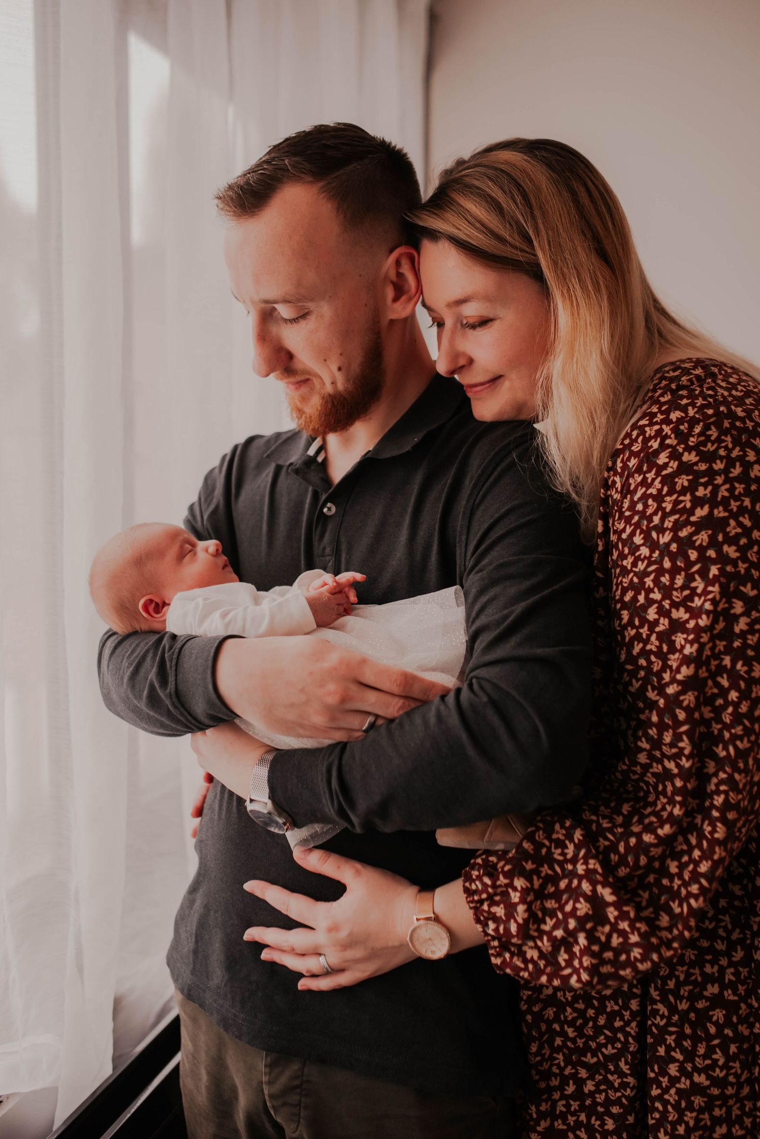 Family portrait series in muted tones showing tender moments with a newborn.