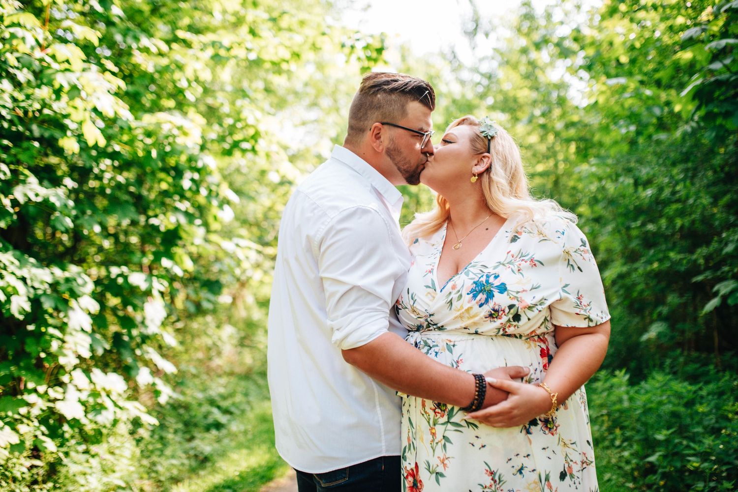 Outdoor maternity photography session captured in a verdant garden setting with soft natural light.