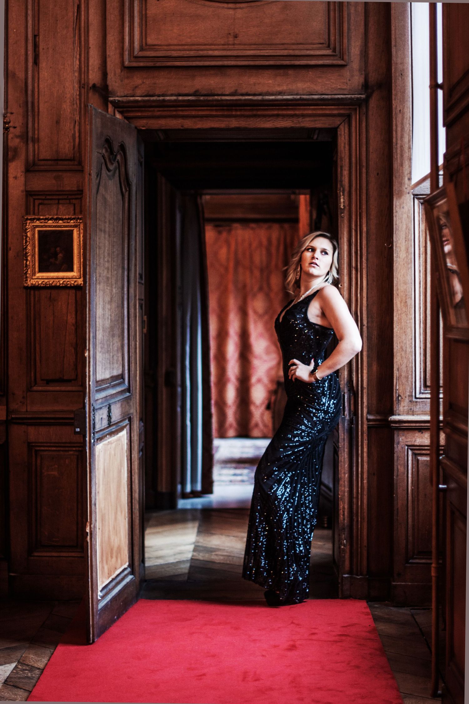 Glamorous portrait series in an ornate vintage room with wood paneling and red carpet.