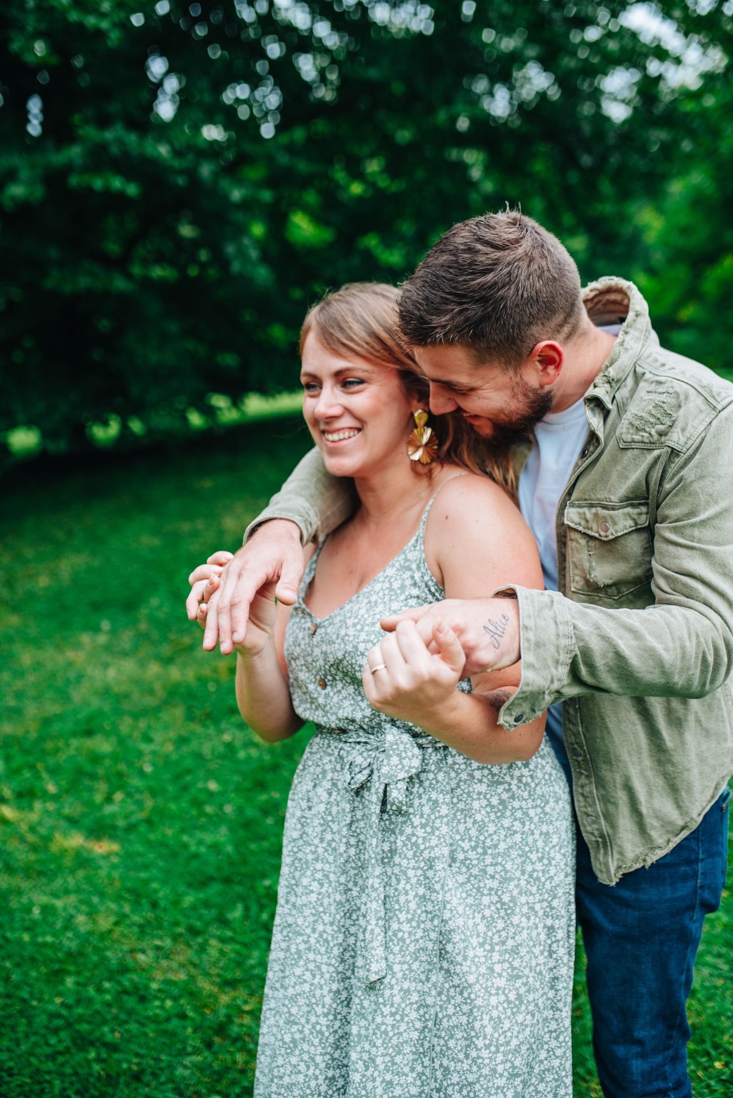 Playful couple sharing tender moments in a green garden setting wearing casual spring attire.