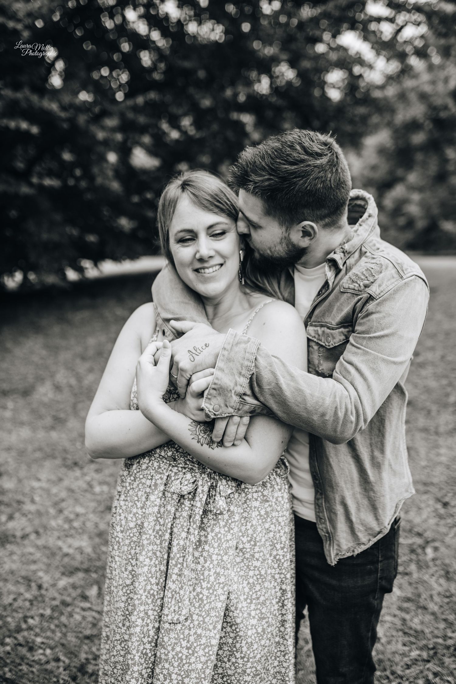Black and white photo of couple sharing intimate moment while holding a small pet.