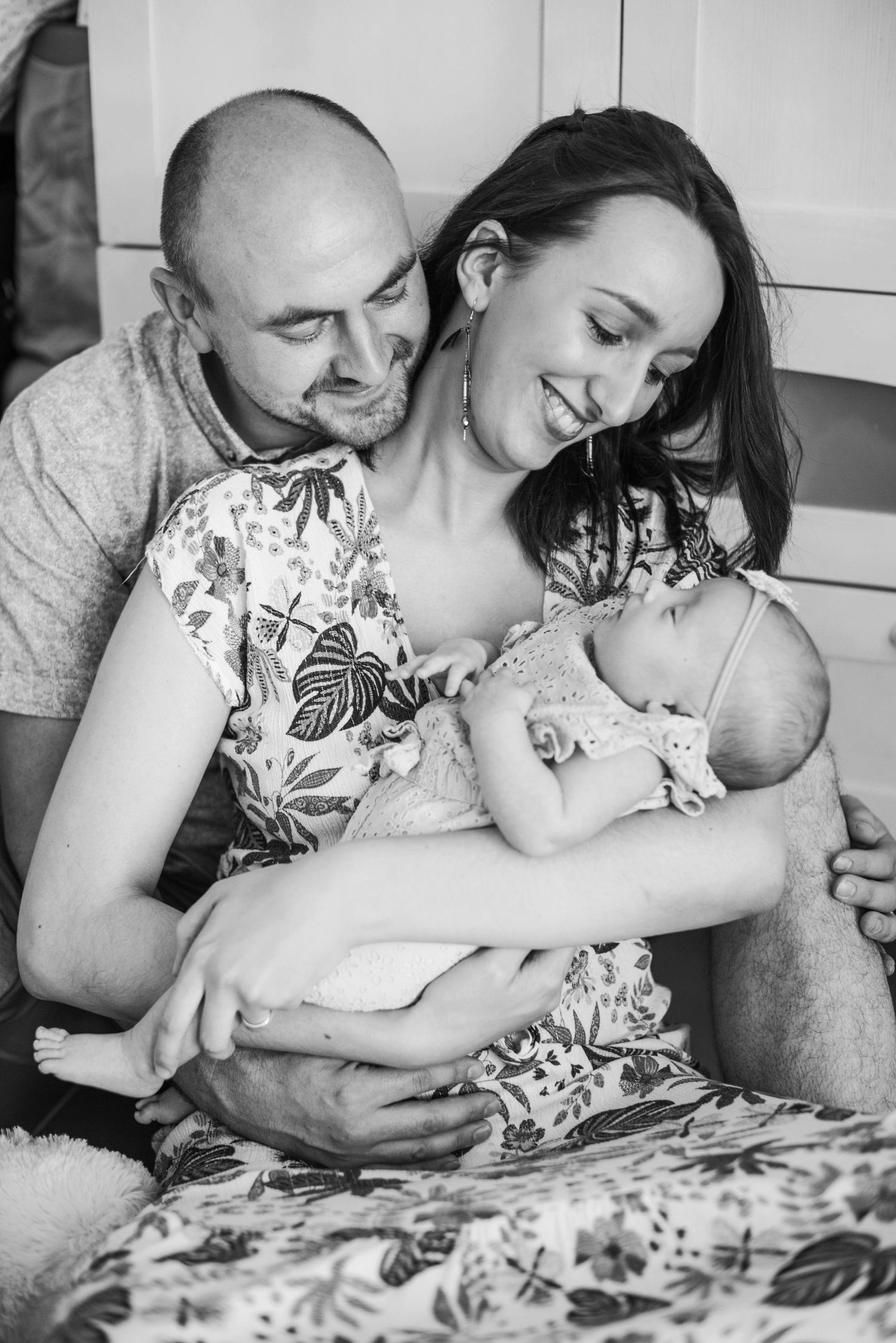 Family shares intimate moment with newborn on floral patterned bedding.