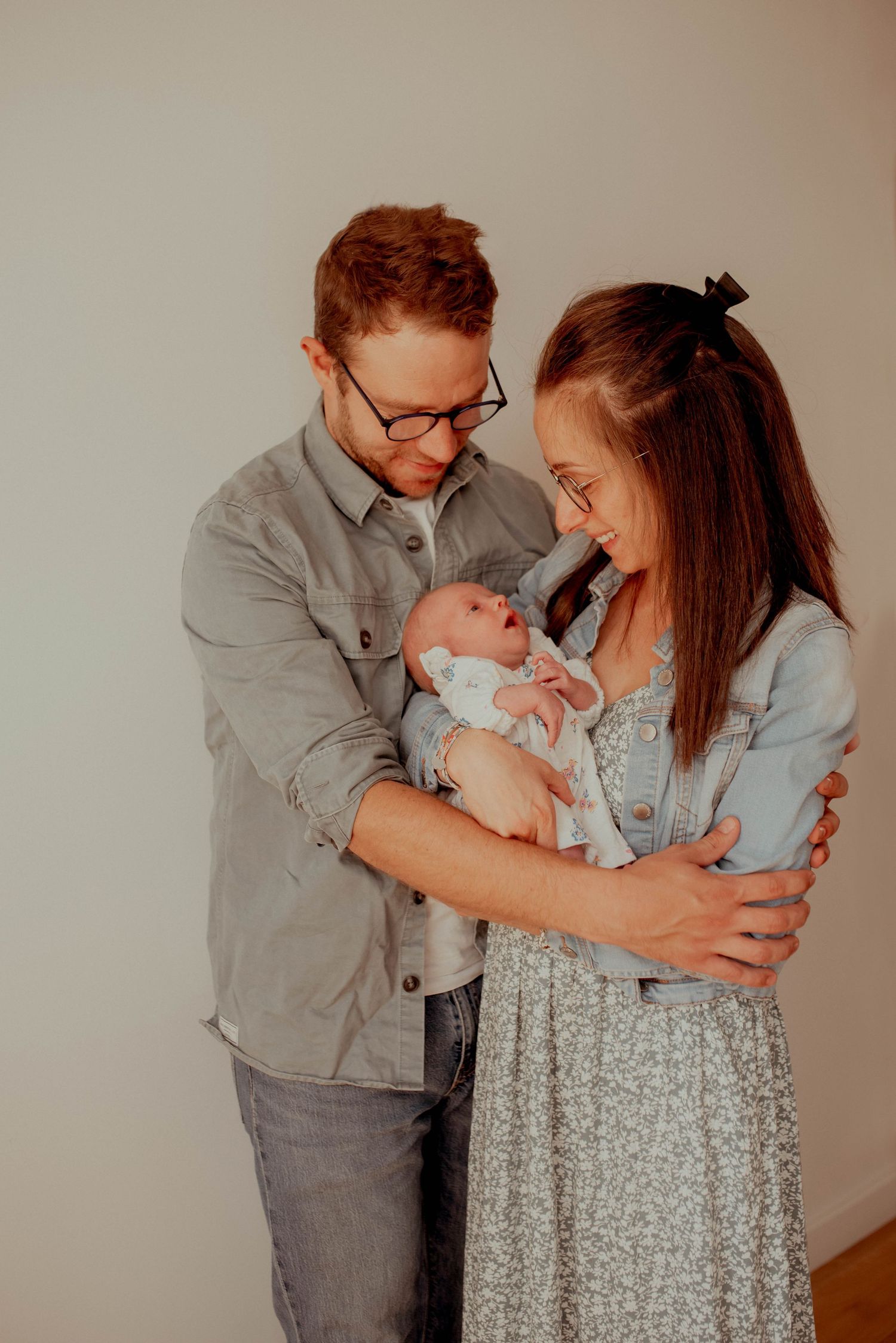 Couple in denim jackets shares tender moment with their newborn baby.