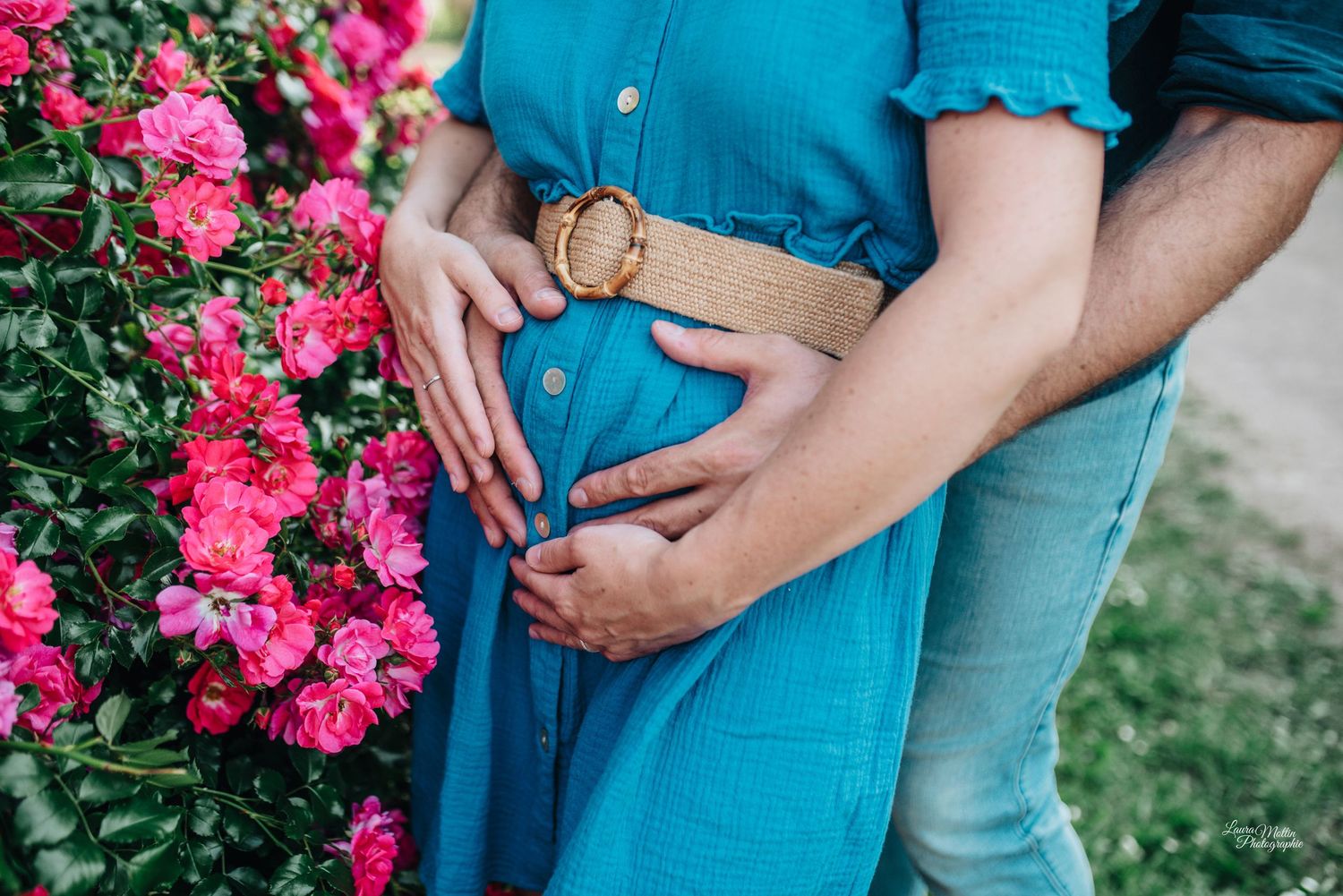 Engagement photo with couple in blue attire near blooming pink flowers.
