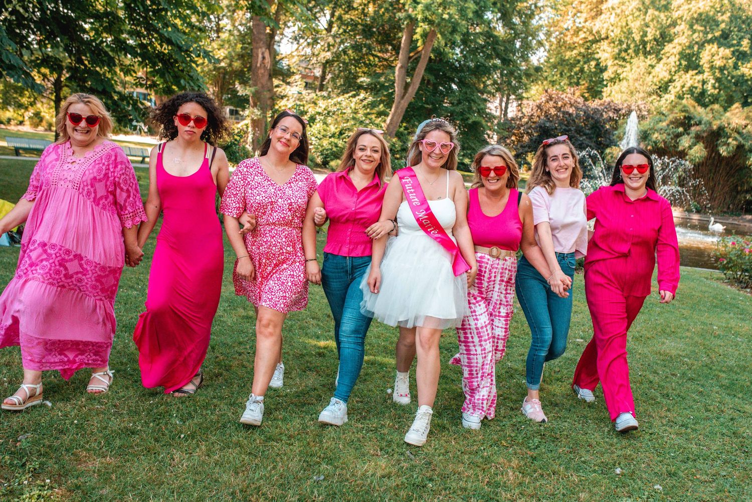 A group walks together outdoors wearing vibrant pink and colorful outfits.